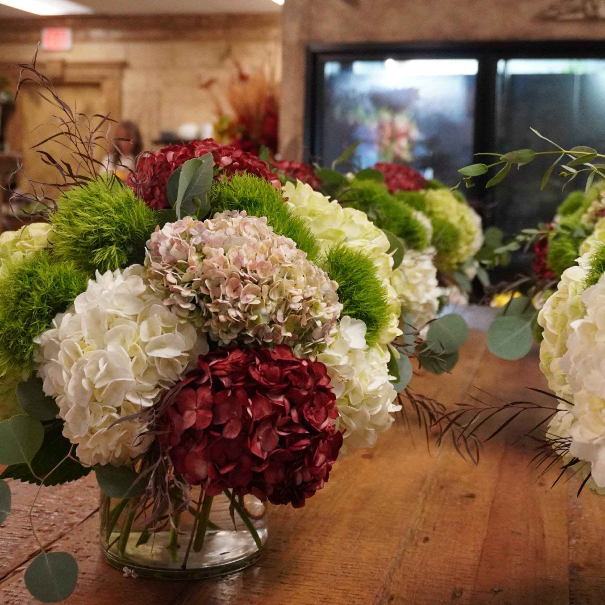 Hydrangea arrangement in a clear glass vase with red, white, and green blooms