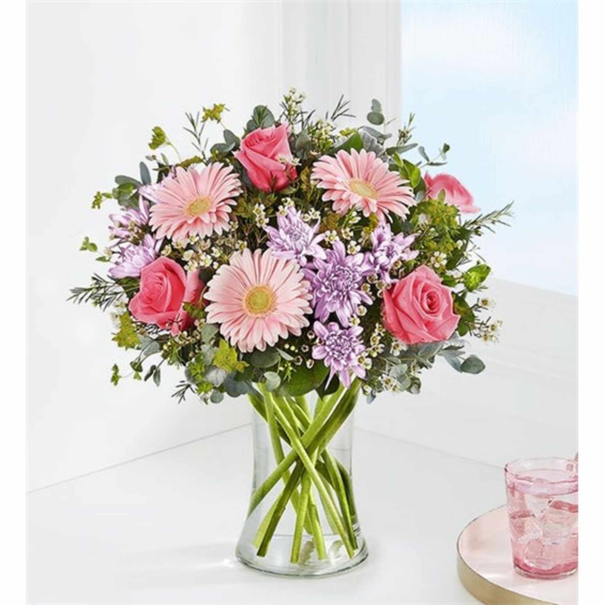 Pink roses and daisies arranged in a clear glass vase