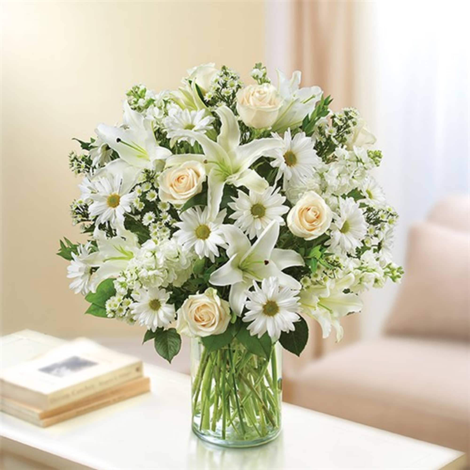 White lilies, daisies, and cream roses in a clear glass vase