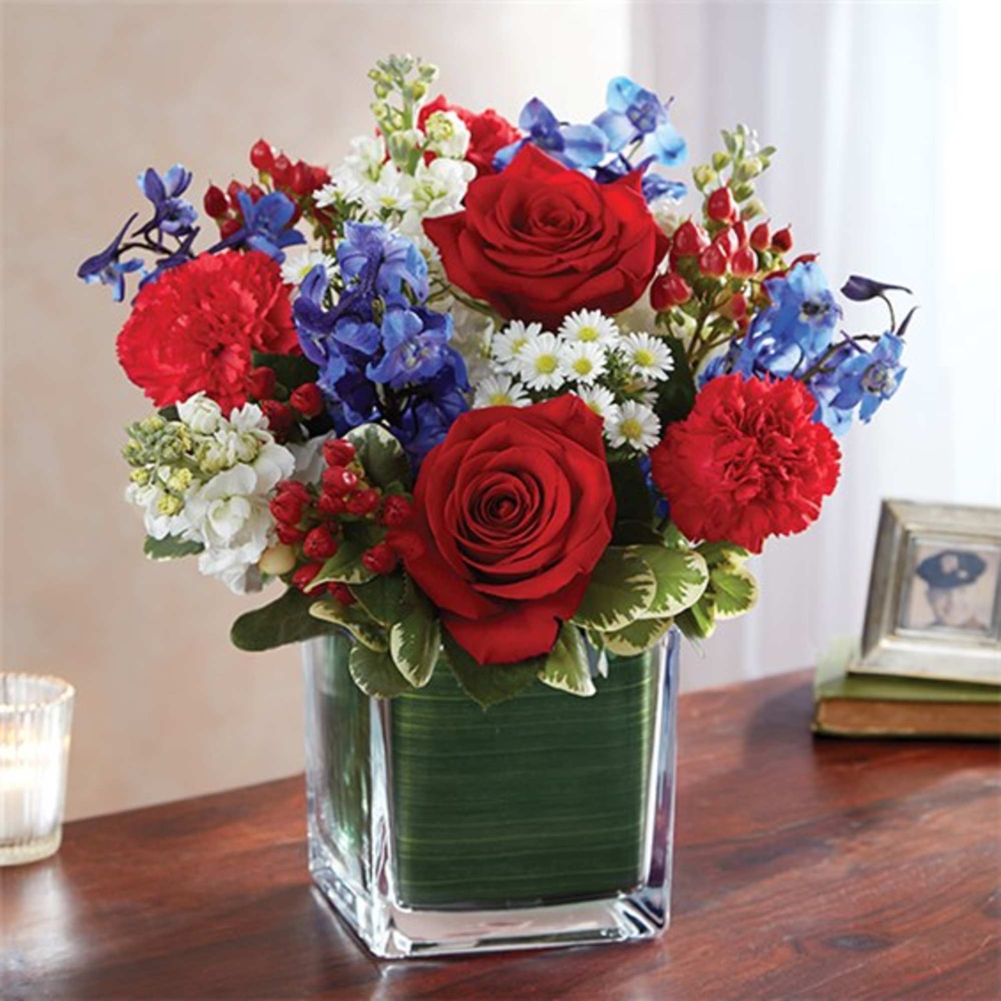 Red roses and blue flowers in a square glass vase
