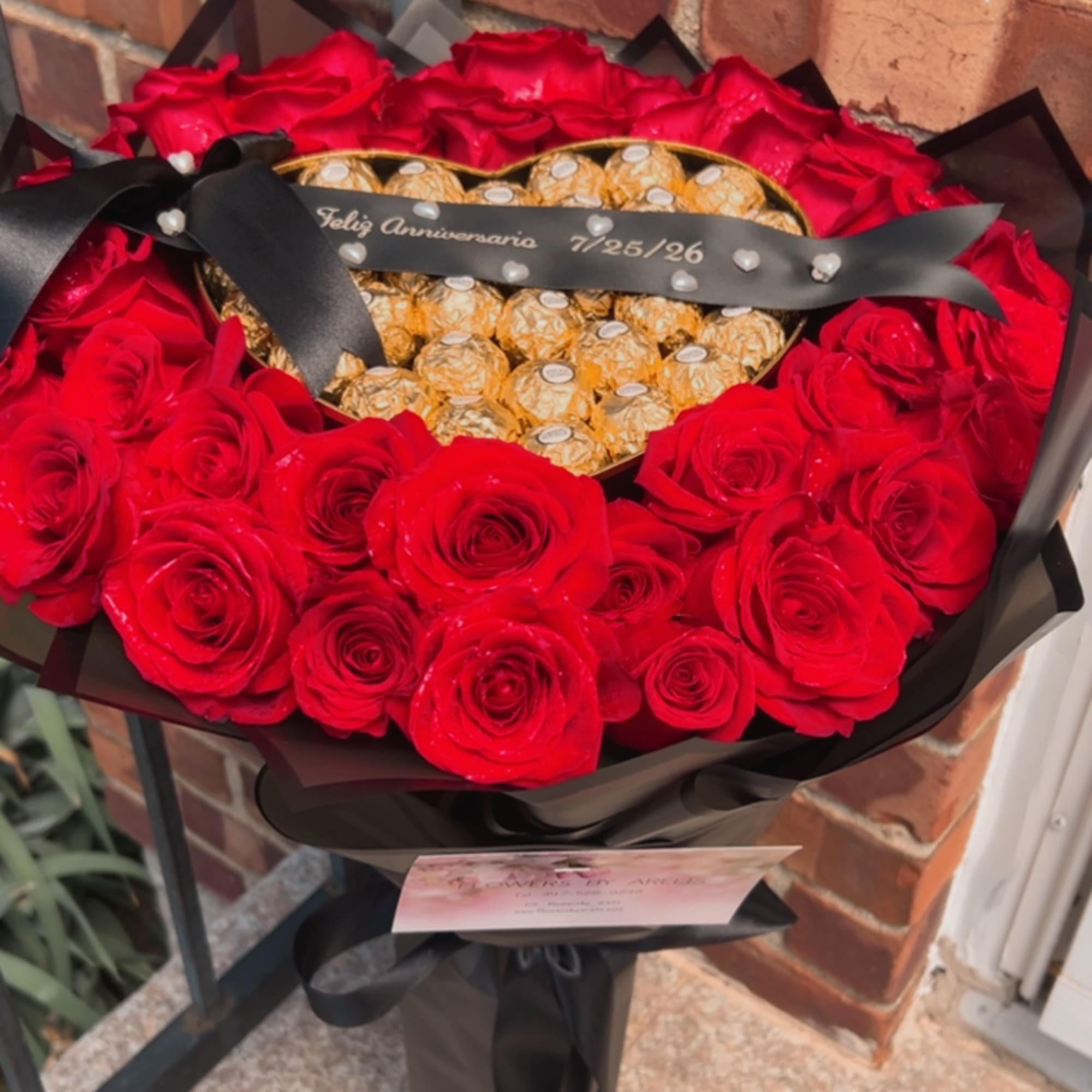 Heart-shaped bouquet of red roses with gold chocolates and a black ribbon