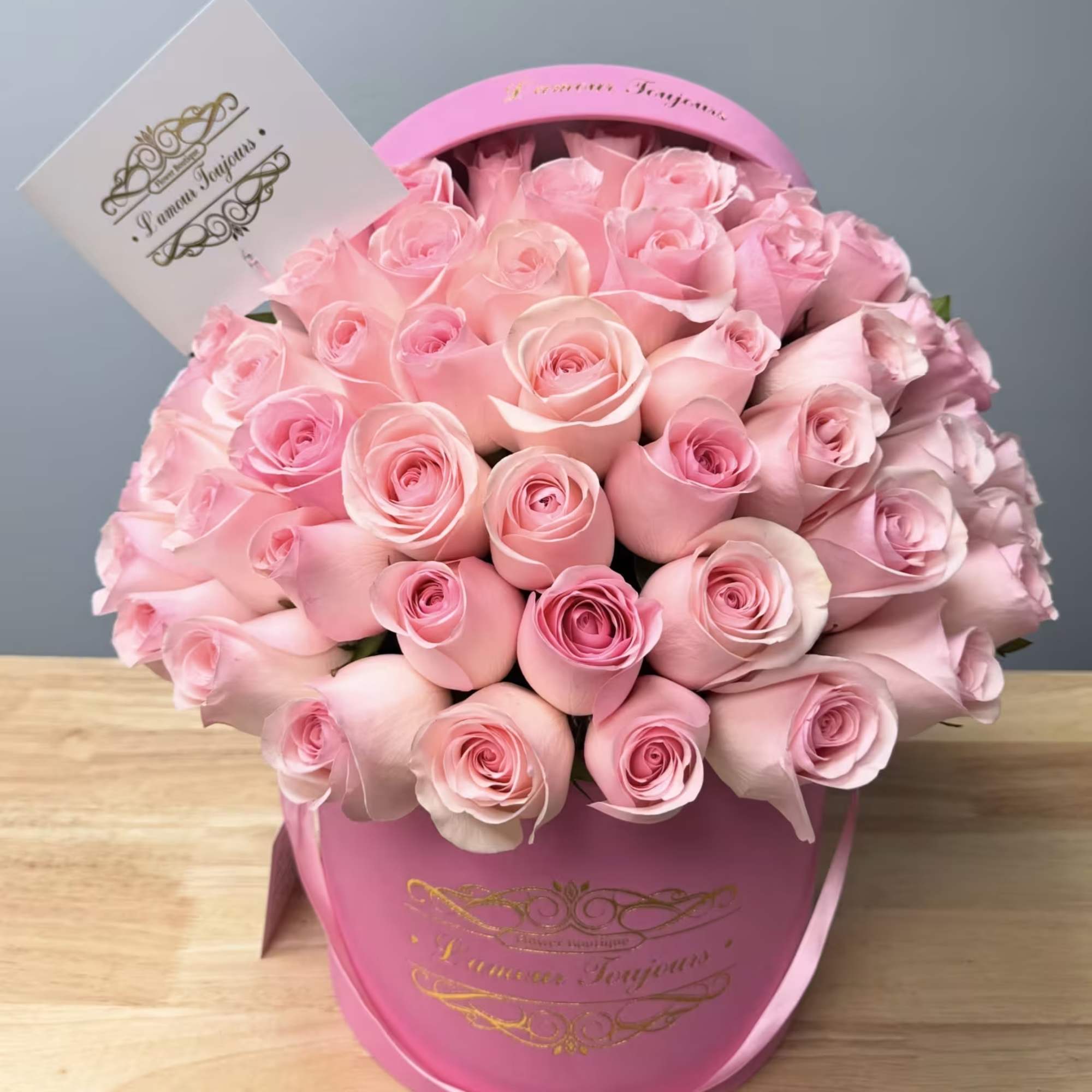 Pink roses arranged in a round hatbox with a card insert