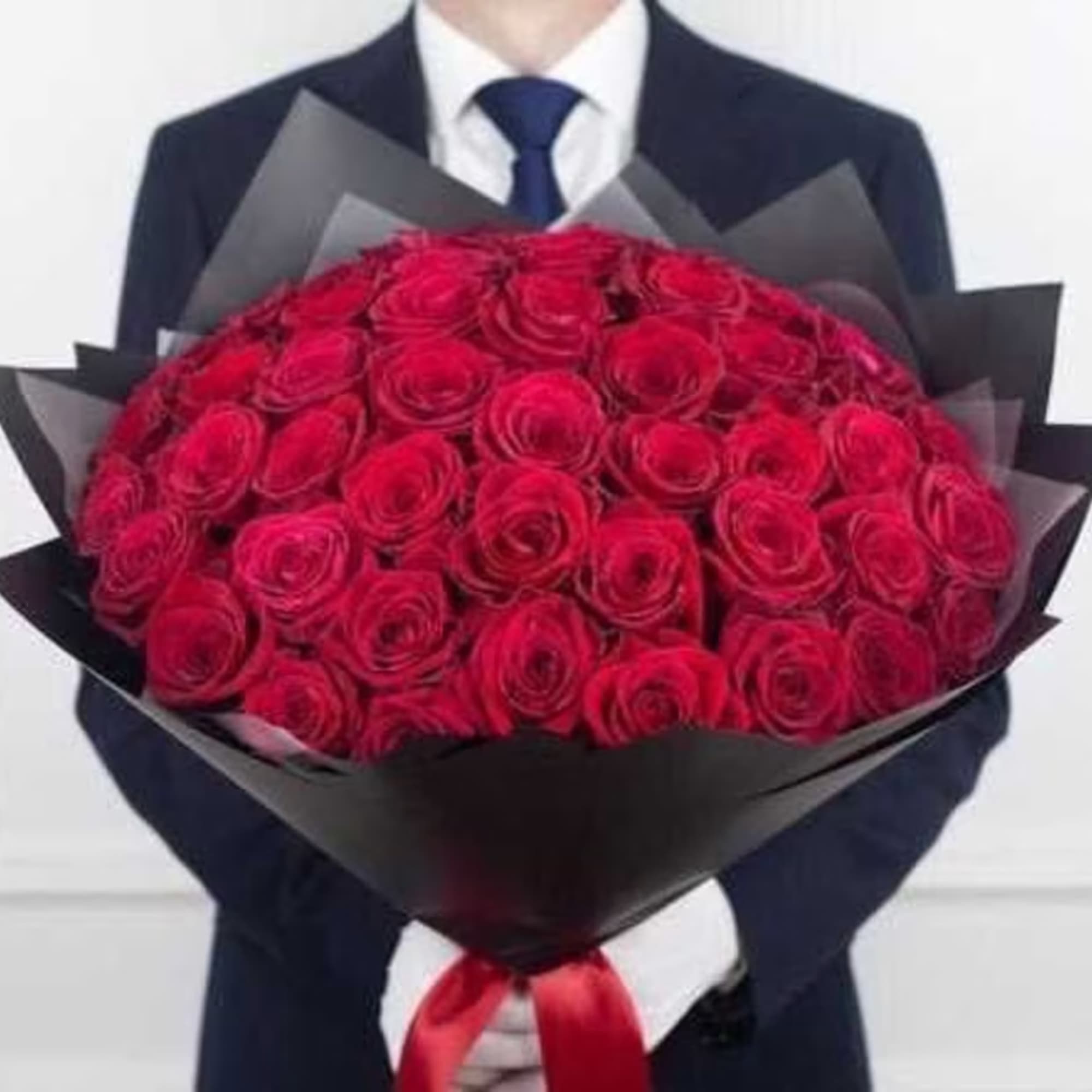 Man holding a large bouquet of red roses wrapped in black paper