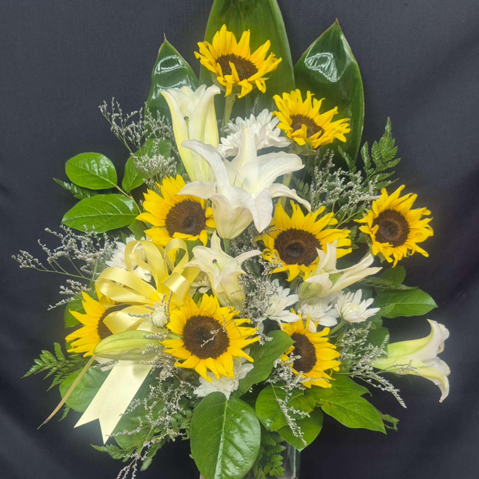 Bouquet of sunflowers and white lilies with a yellow ribbon