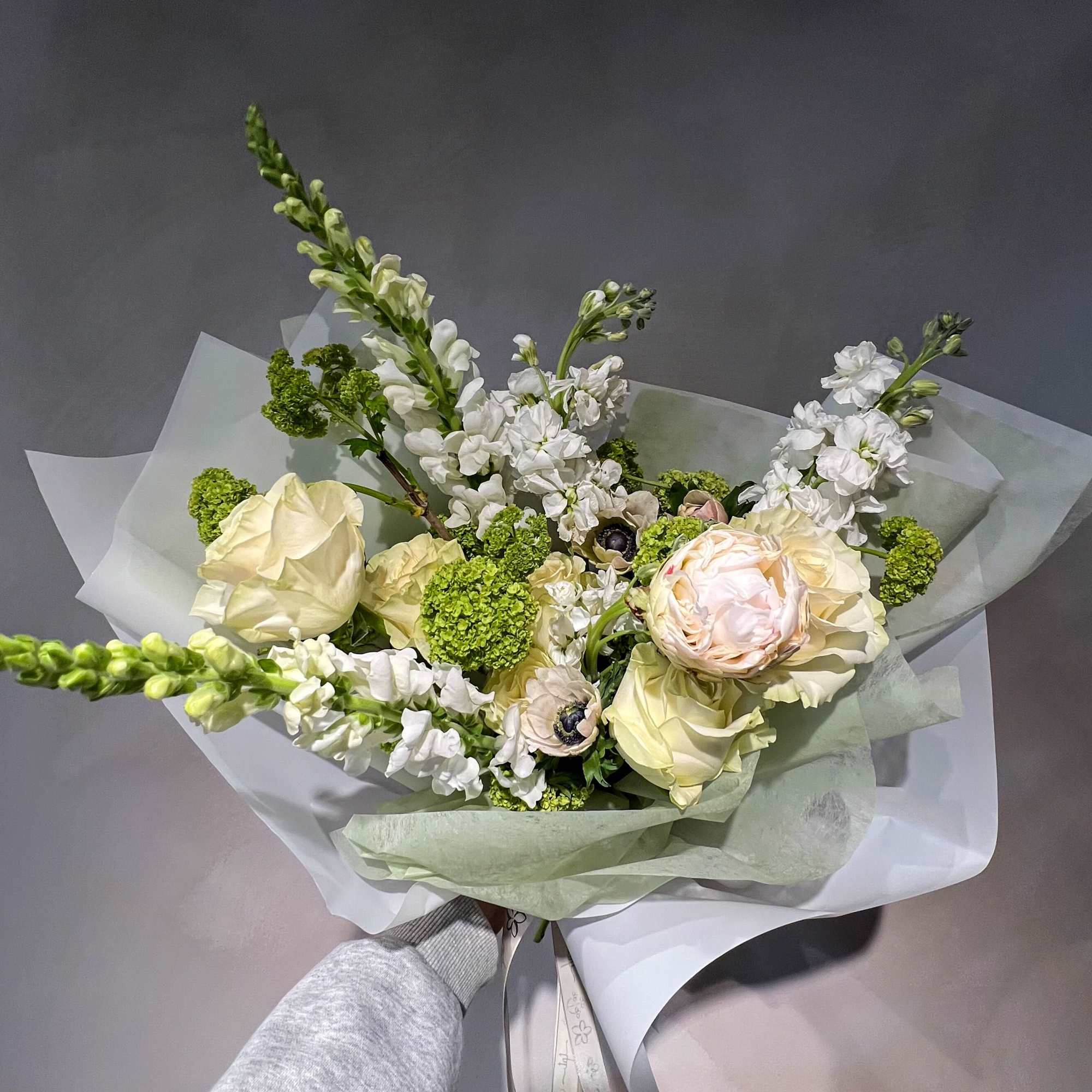 Bouquet of pale cream and white flowers wrapped in translucent paper