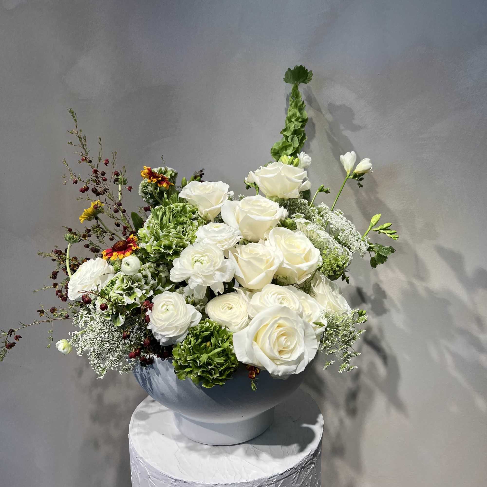 White rose and ranunculus arrangement in a round vase