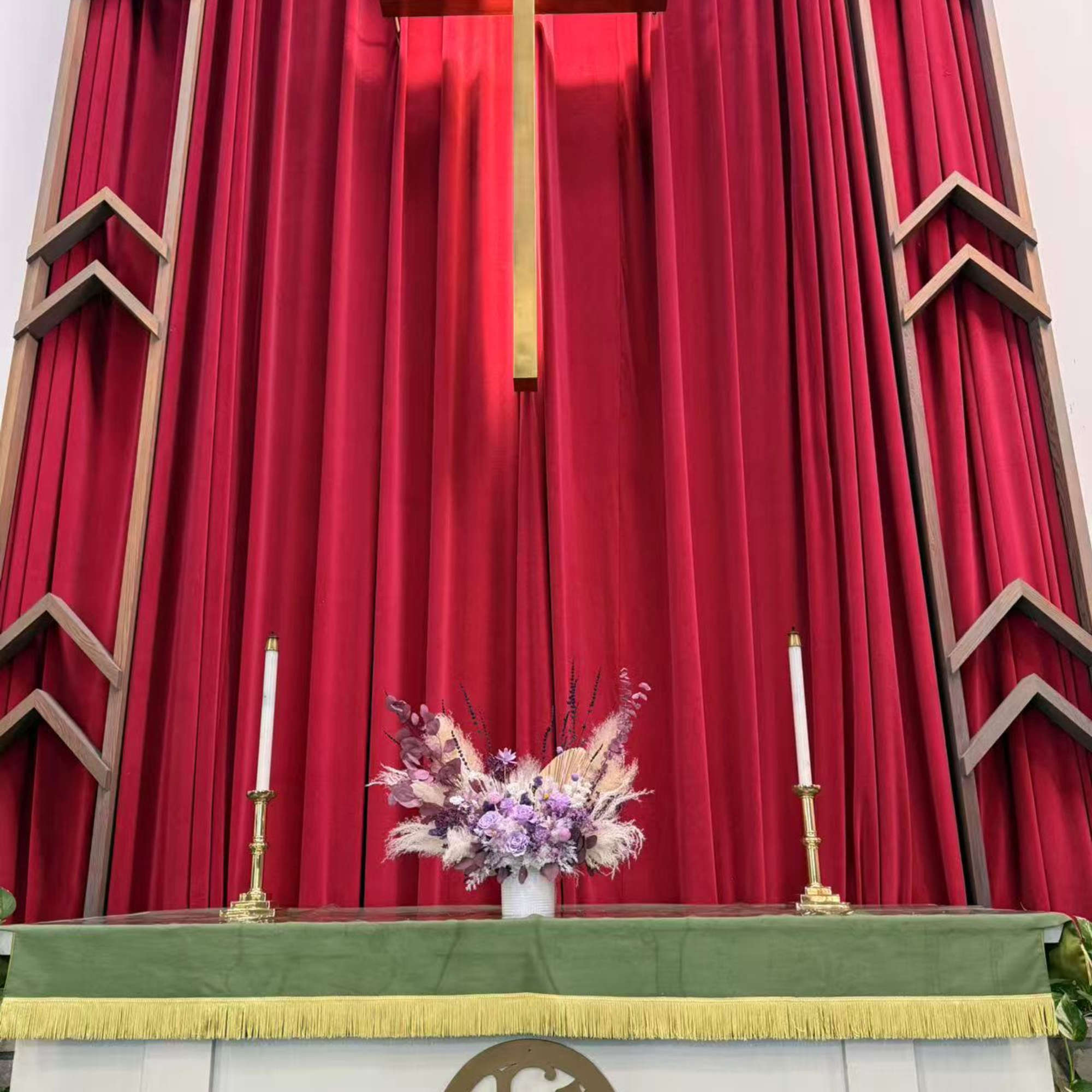 Church altar with a pastel floral arrangement beneath a gold cross