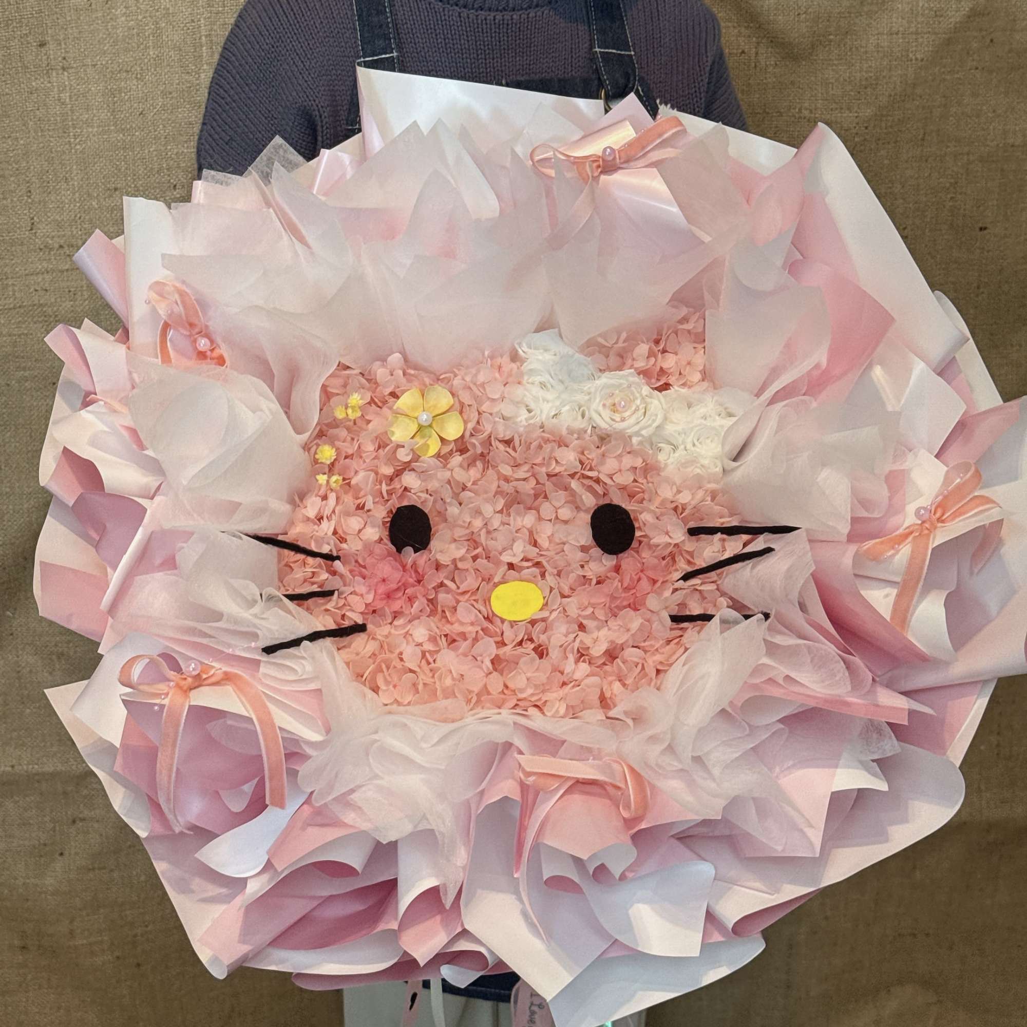Large pink novelty bouquet with Hello Kitty style face made of clustered flowers and paper wrap
