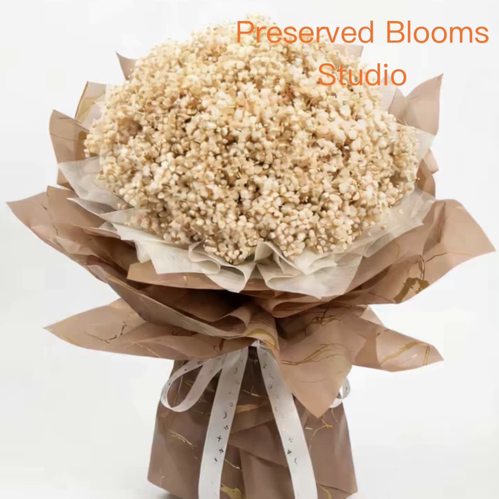 Large bouquet of small cream preserved flowers wrapped in layered brown paper with white ribbon