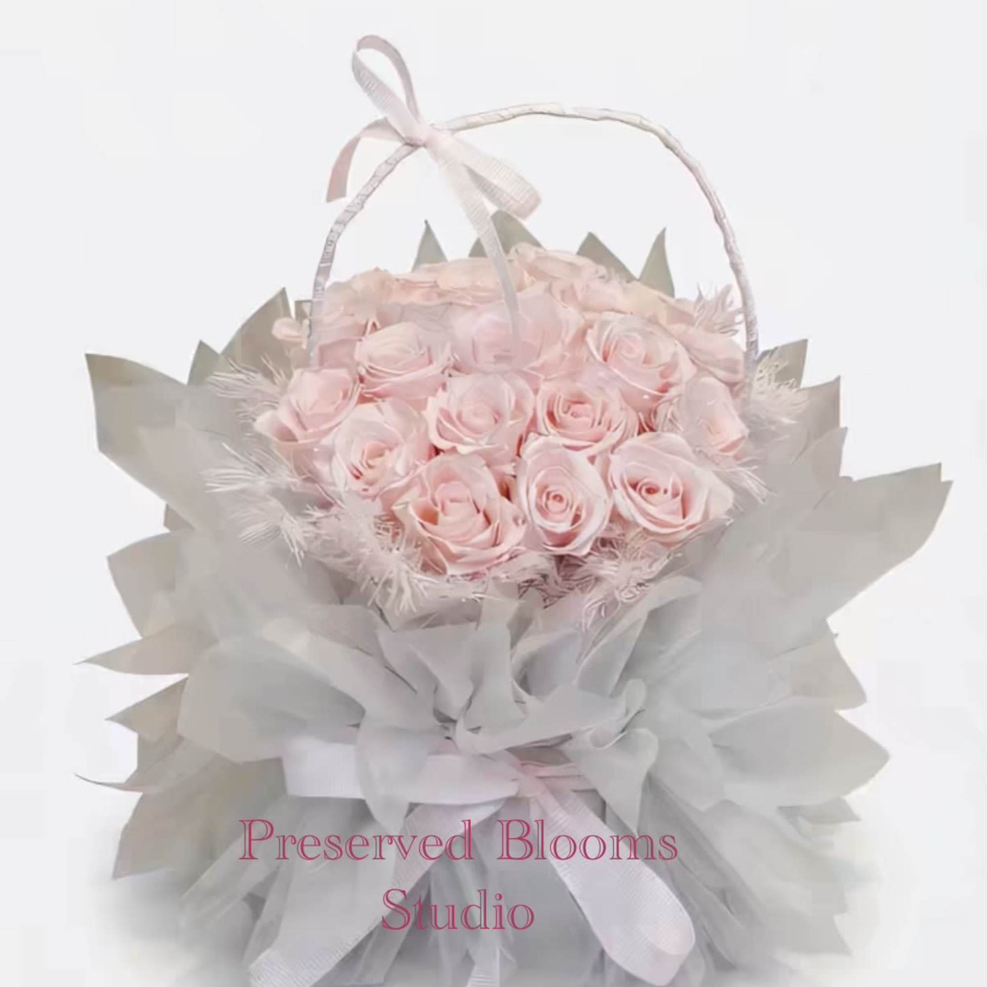 Round basket of pale pink roses wrapped in soft gray tulle with a ribbon handle