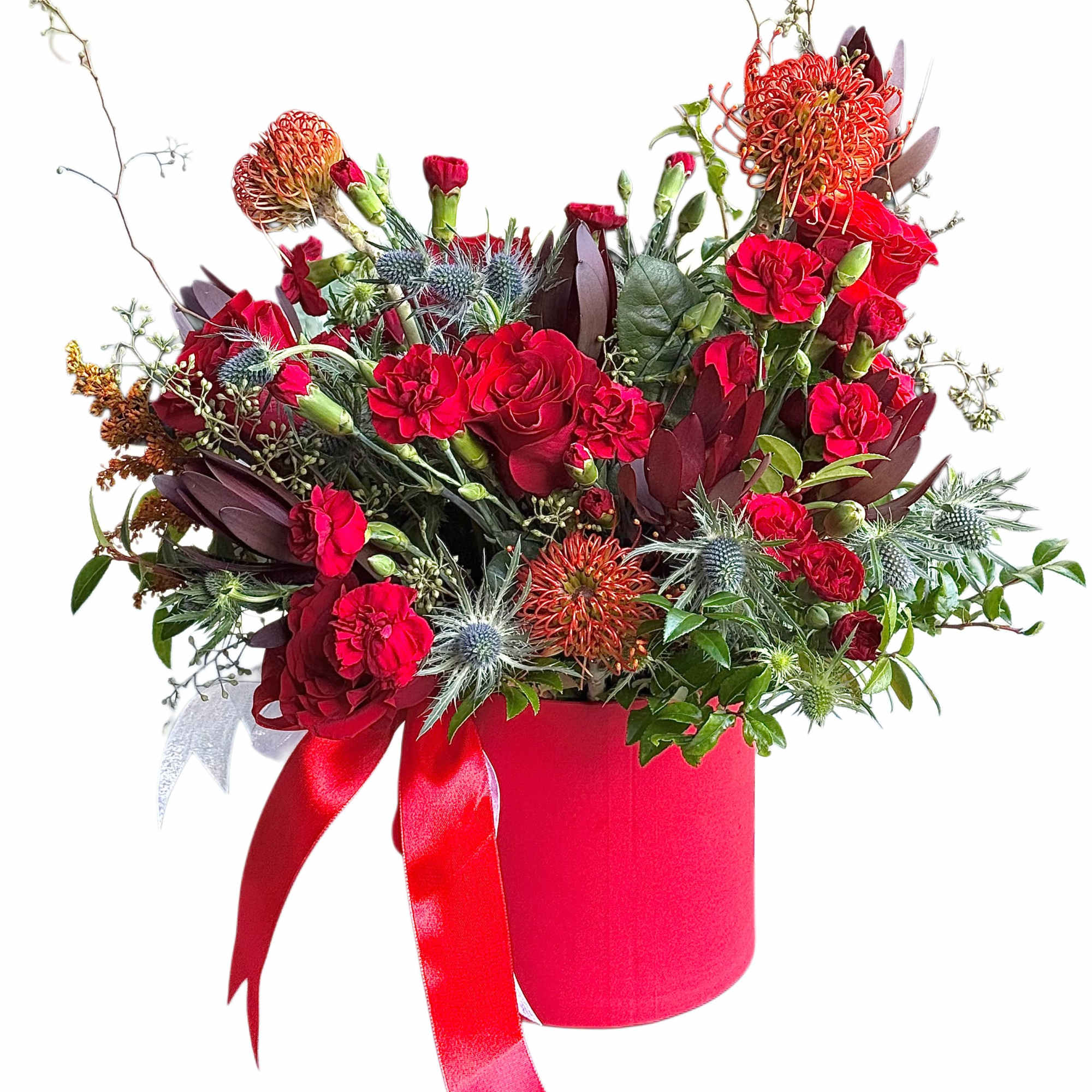 Red floral arrangement in a pink hatbox with ribbon