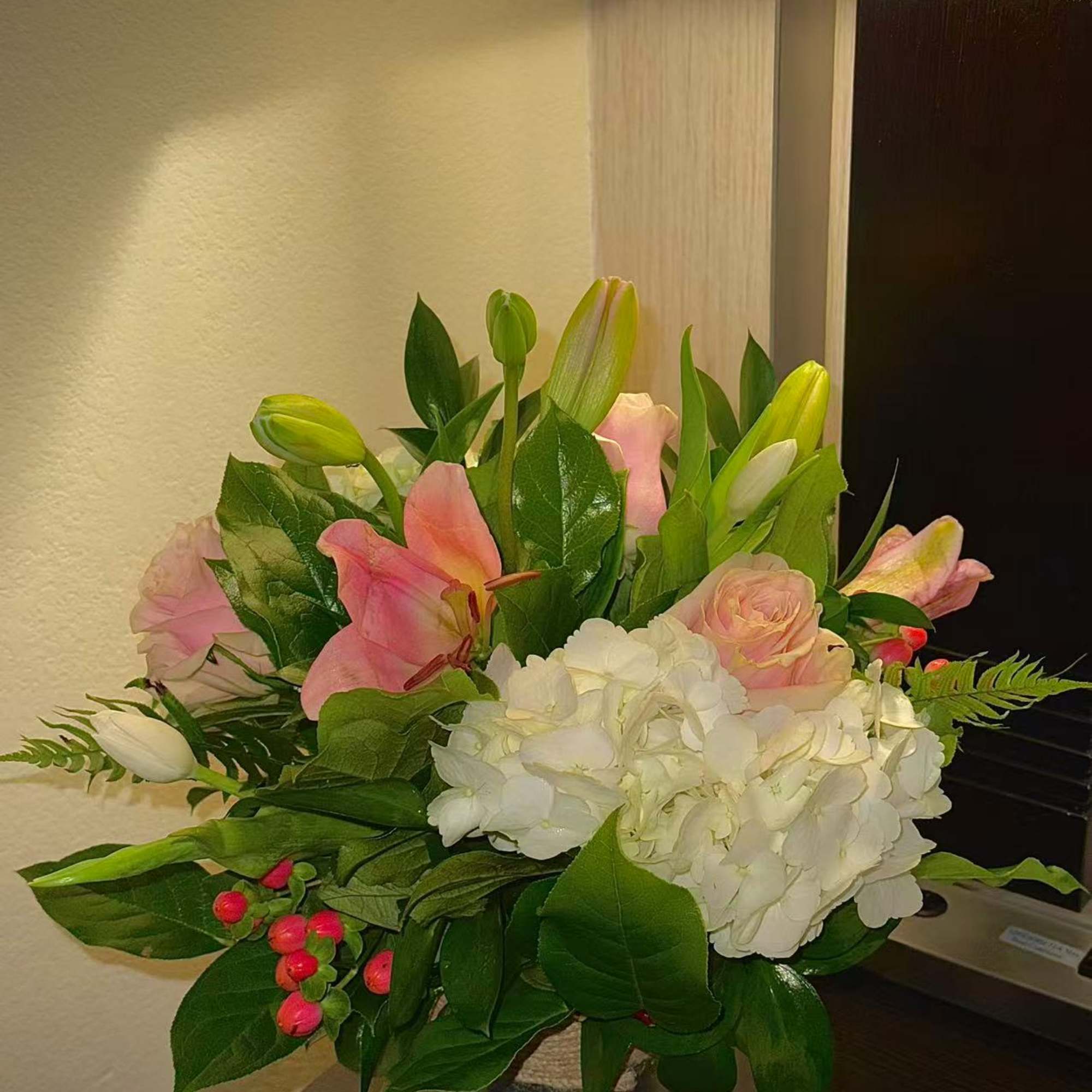 Pink lilies and roses with white hydrangeas in a clear vase