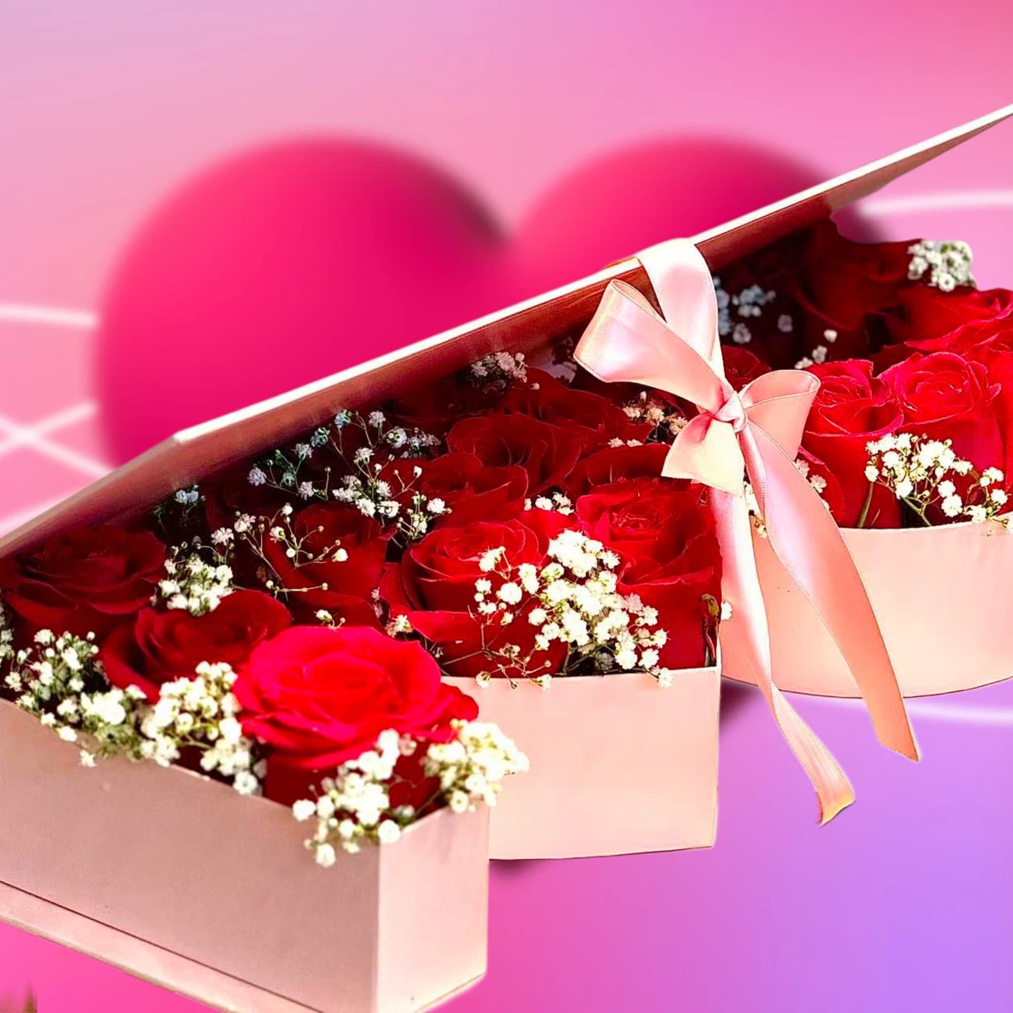 Pink heart-shaped box of red roses with baby's breath and a ribbon