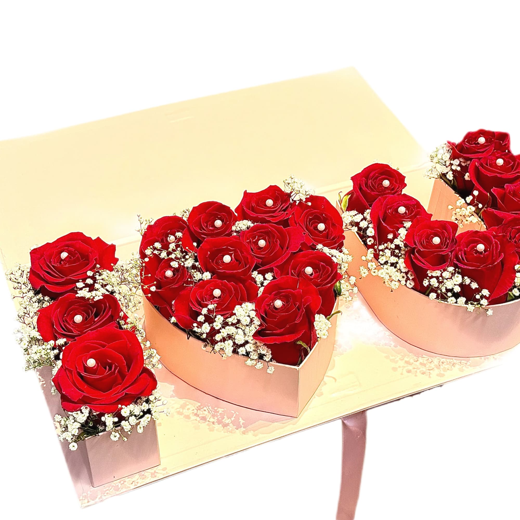 Heart-shaped boxes filled with red roses and baby's breath