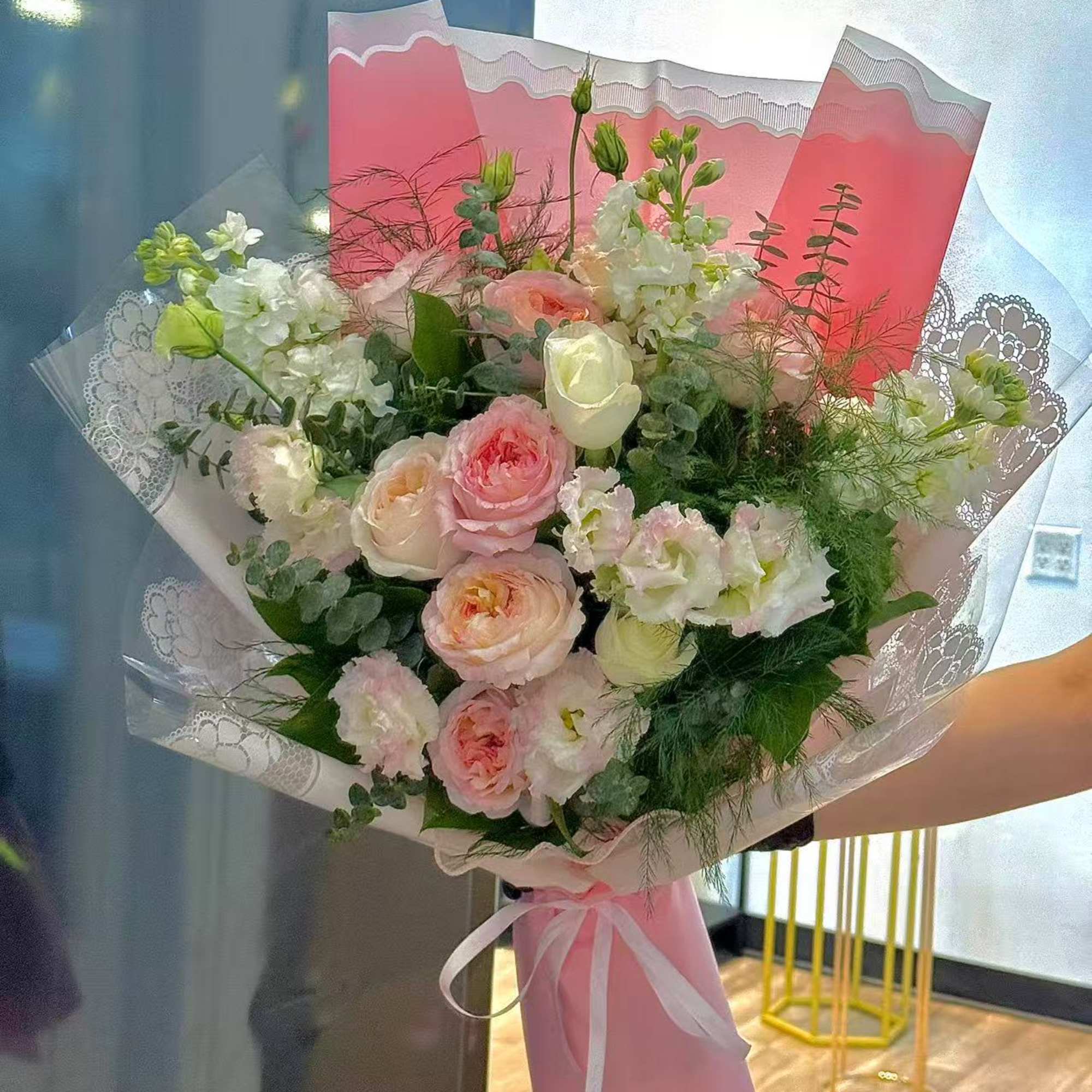 Pink and white bouquet with roses and ruffled blooms wrapped in pink paper