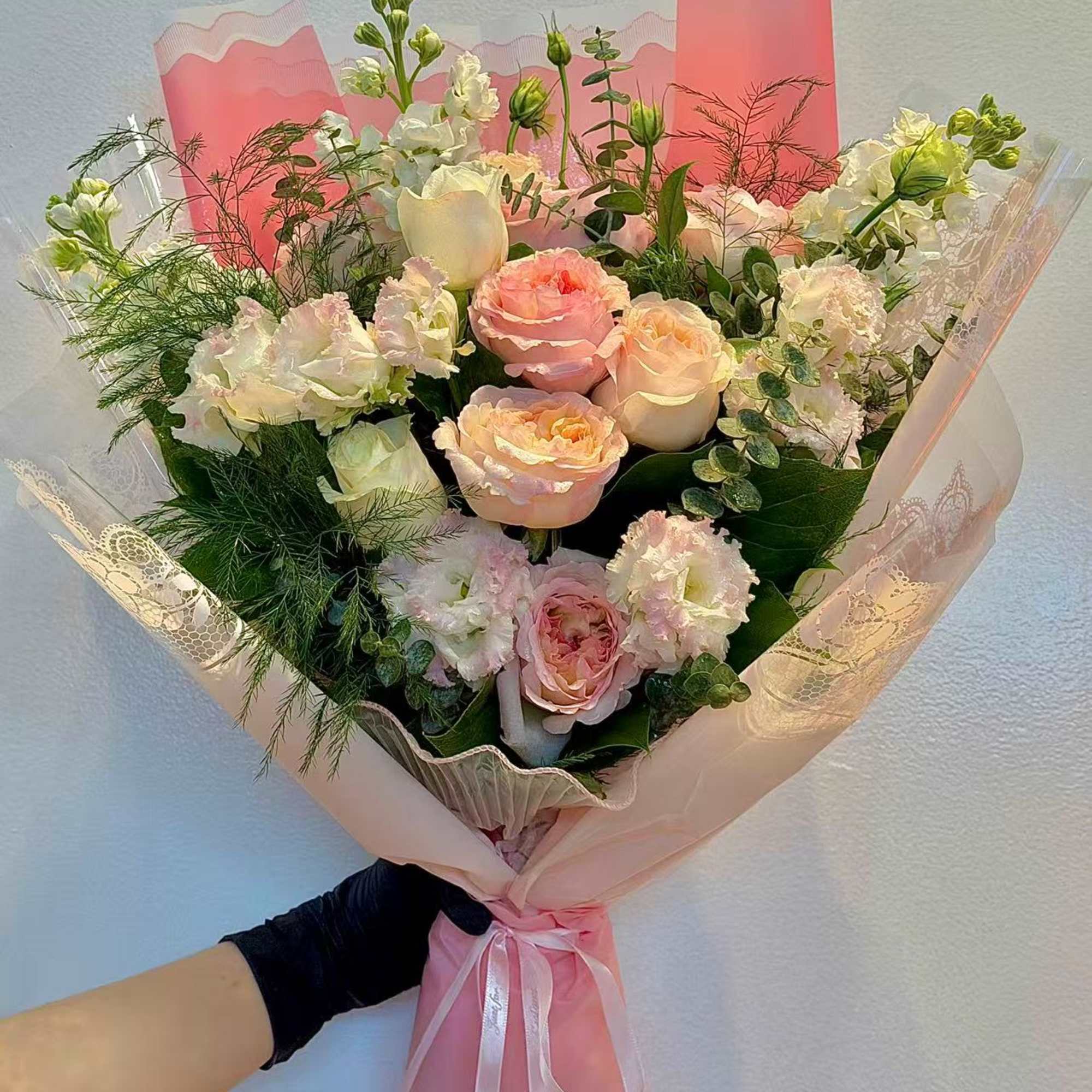Handheld bouquet of pink and white roses with lace wrapping