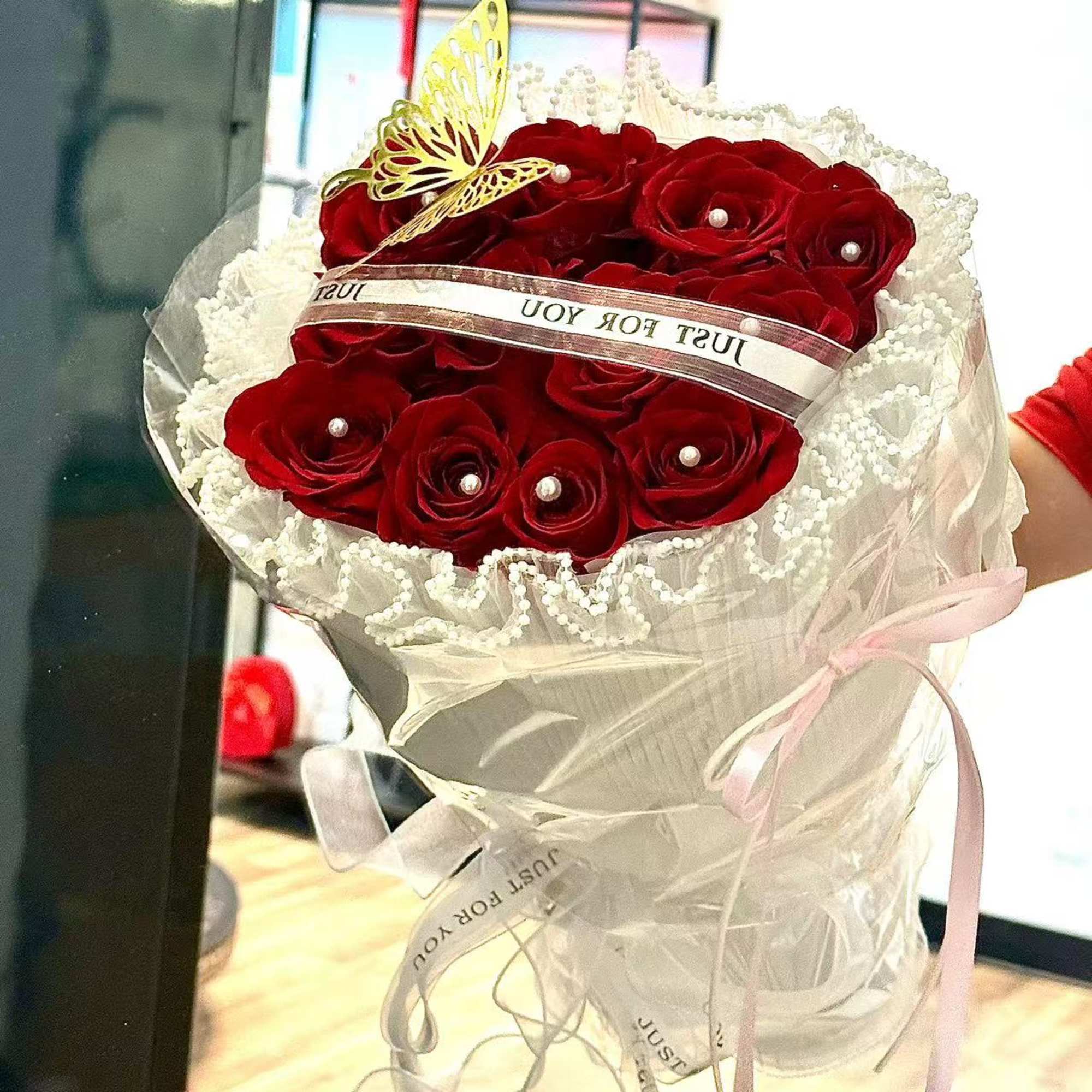 Bouquet of red roses wrapped in white lace and ribbon