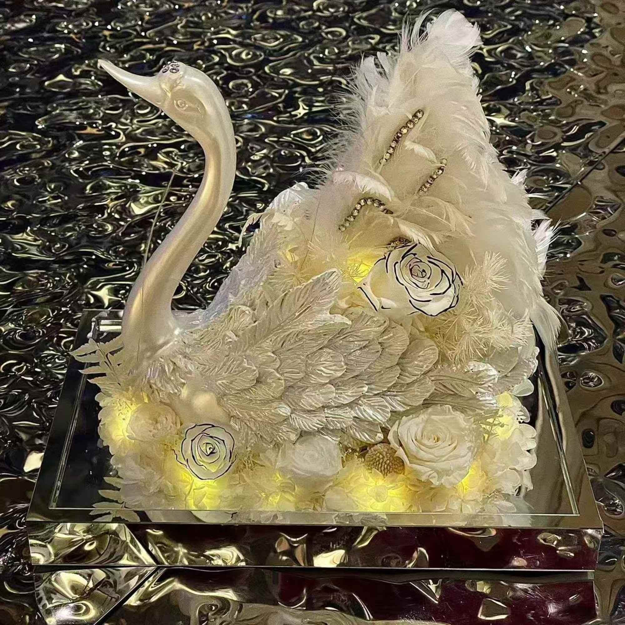 White floral swan sculpture with feathers and roses on a mirrored base