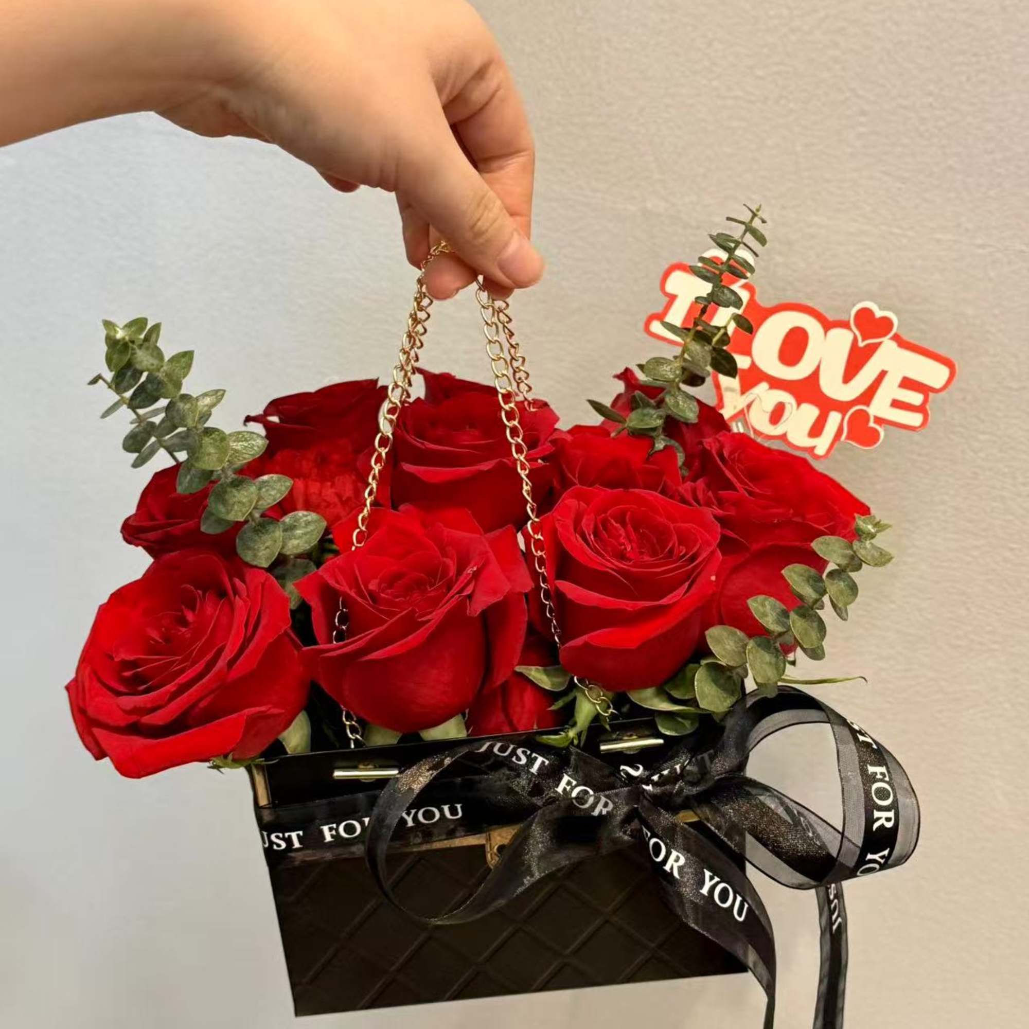 Red roses in a black gift box with a "Love you" sign