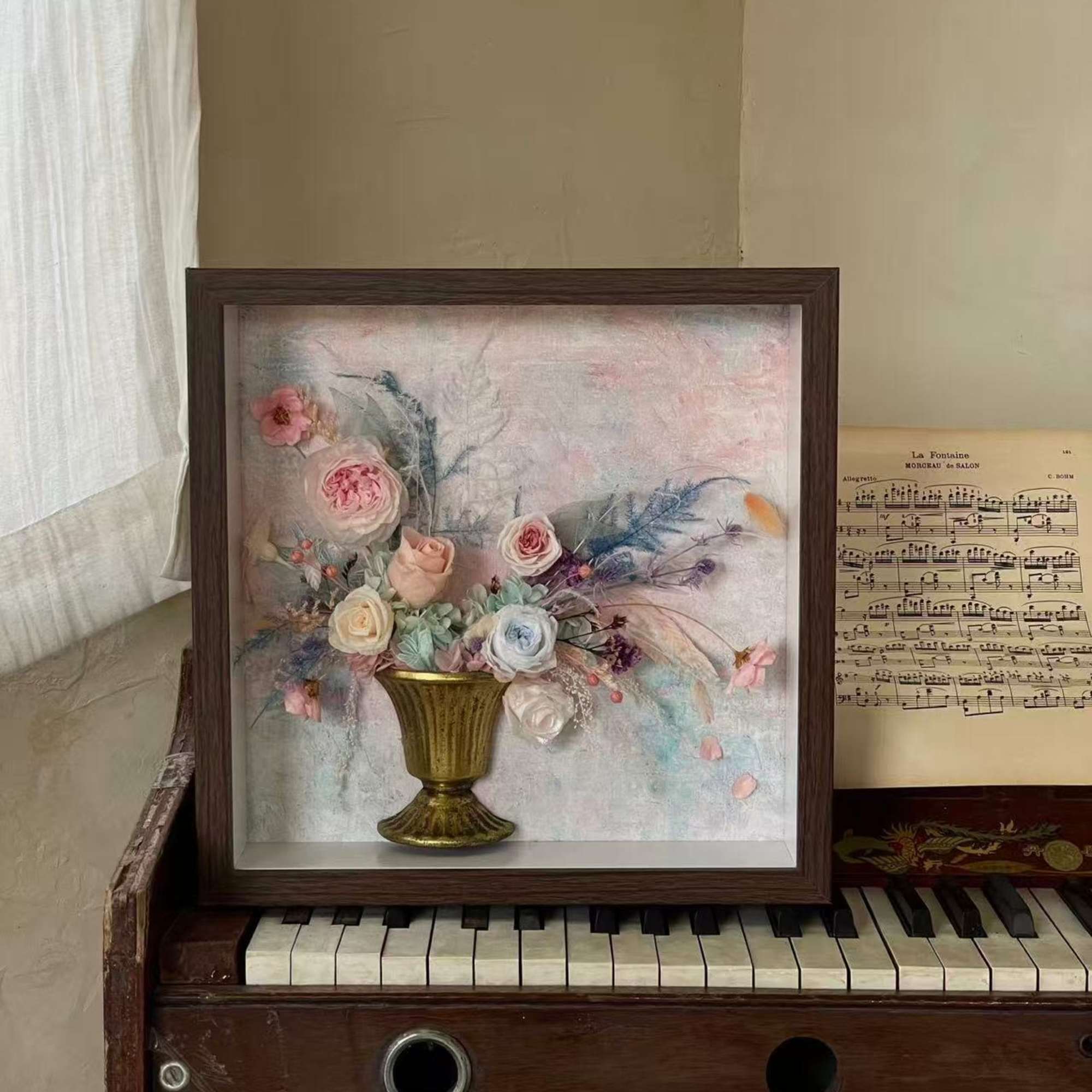 Framed floral arrangement with pastel roses in a gold vase