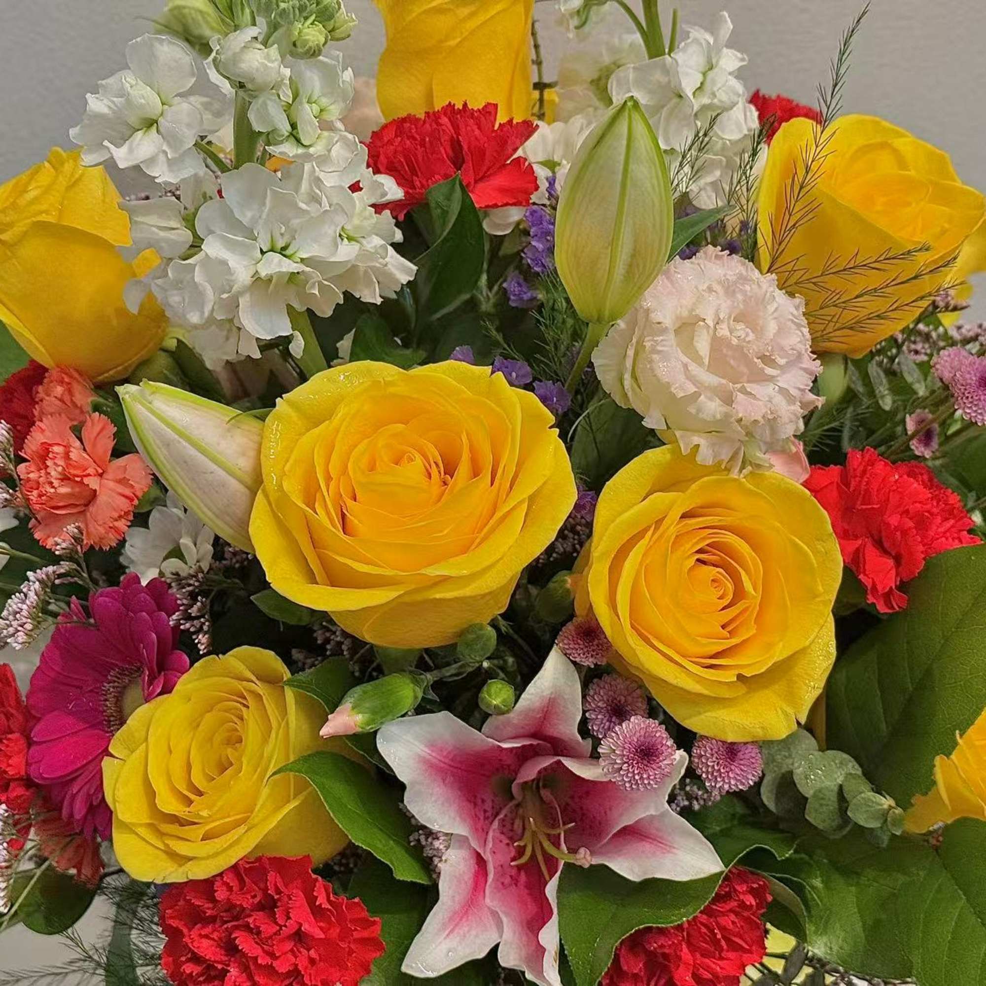 Mixed bouquet with yellow roses, red carnations, and white lilies