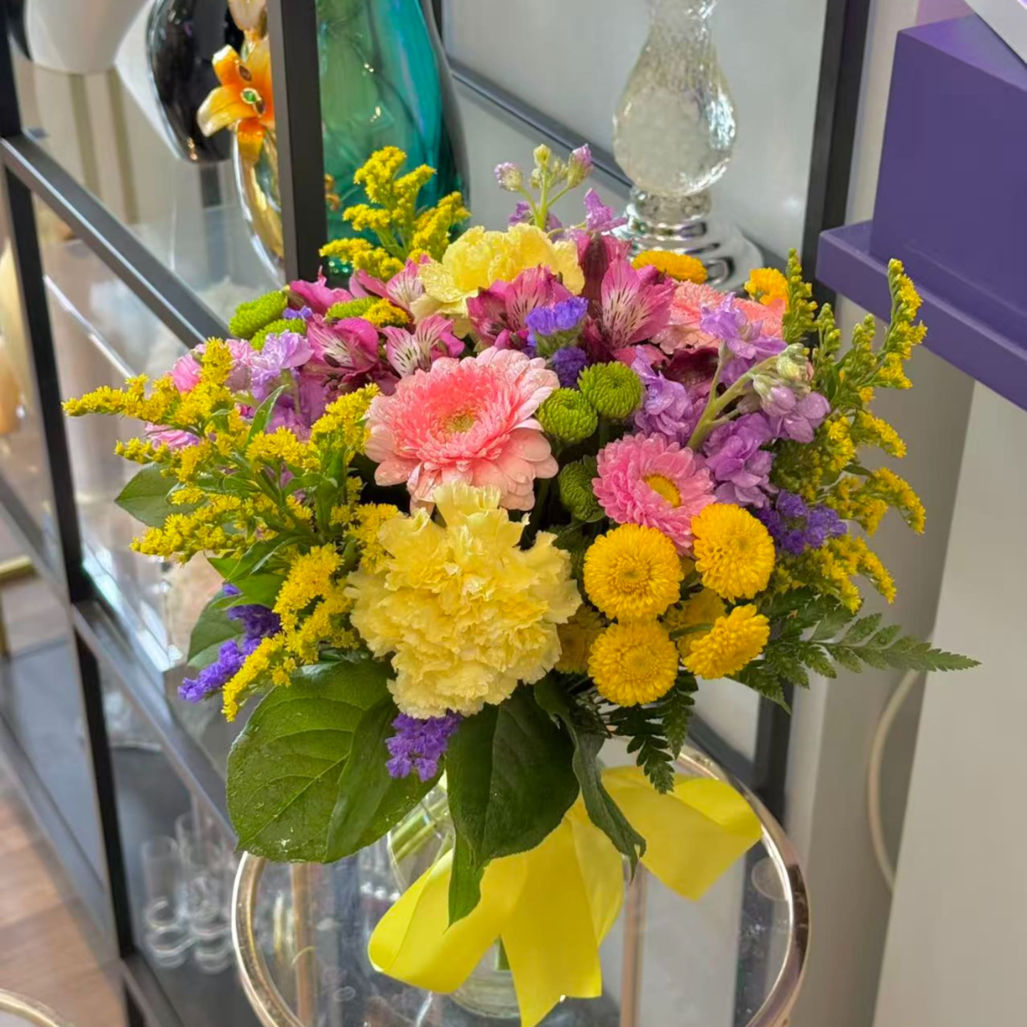 Colorful mixed bouquet in a clear vase with a yellow ribbon