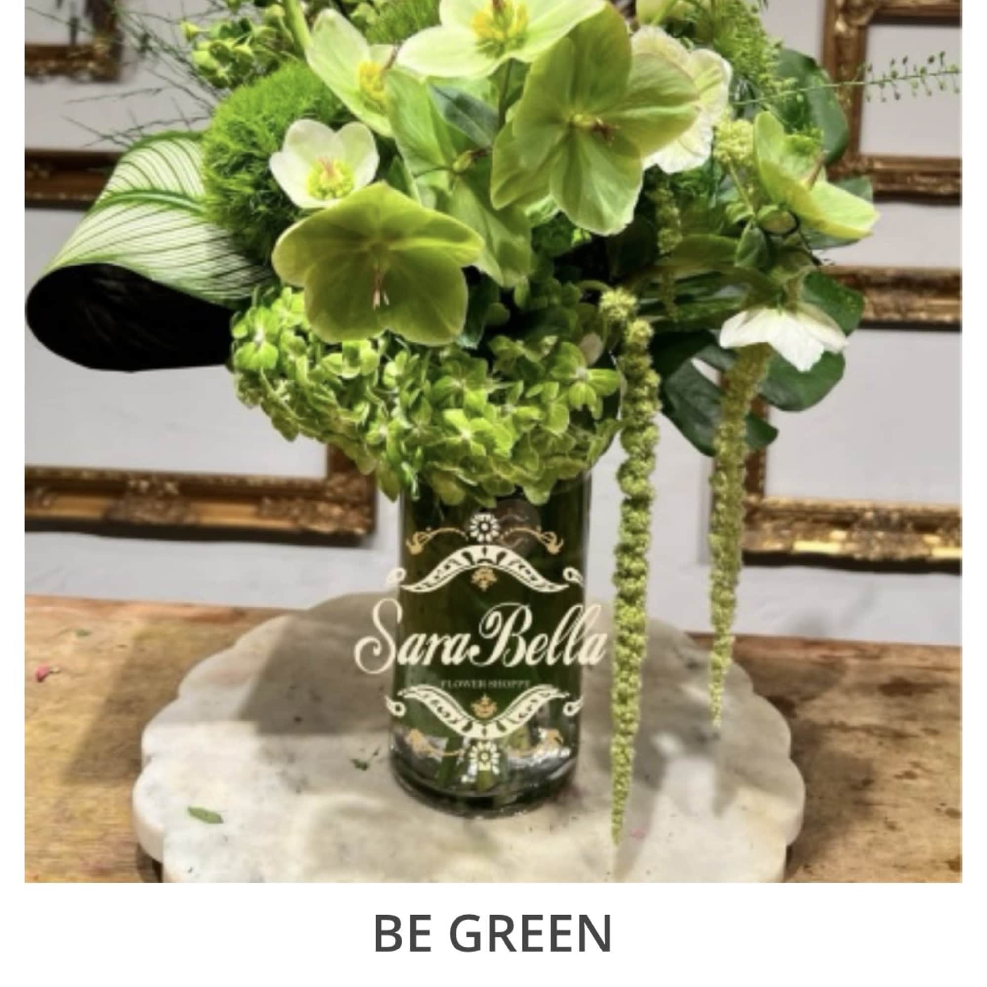 Green floral arrangement in a dark glass vase