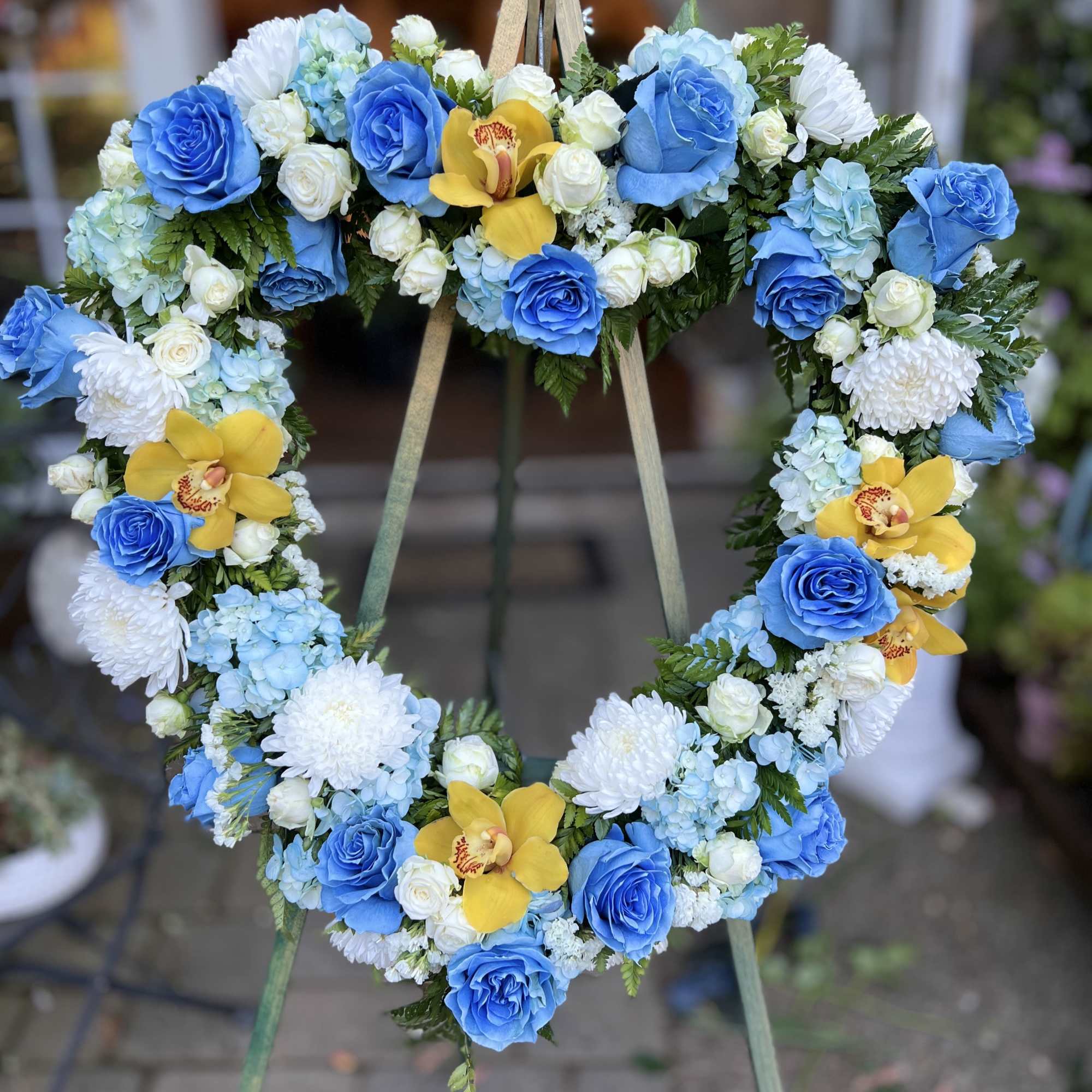 funeral wreath with blue roses, hydrangeas,  spray rose, and cymbidium orchids
