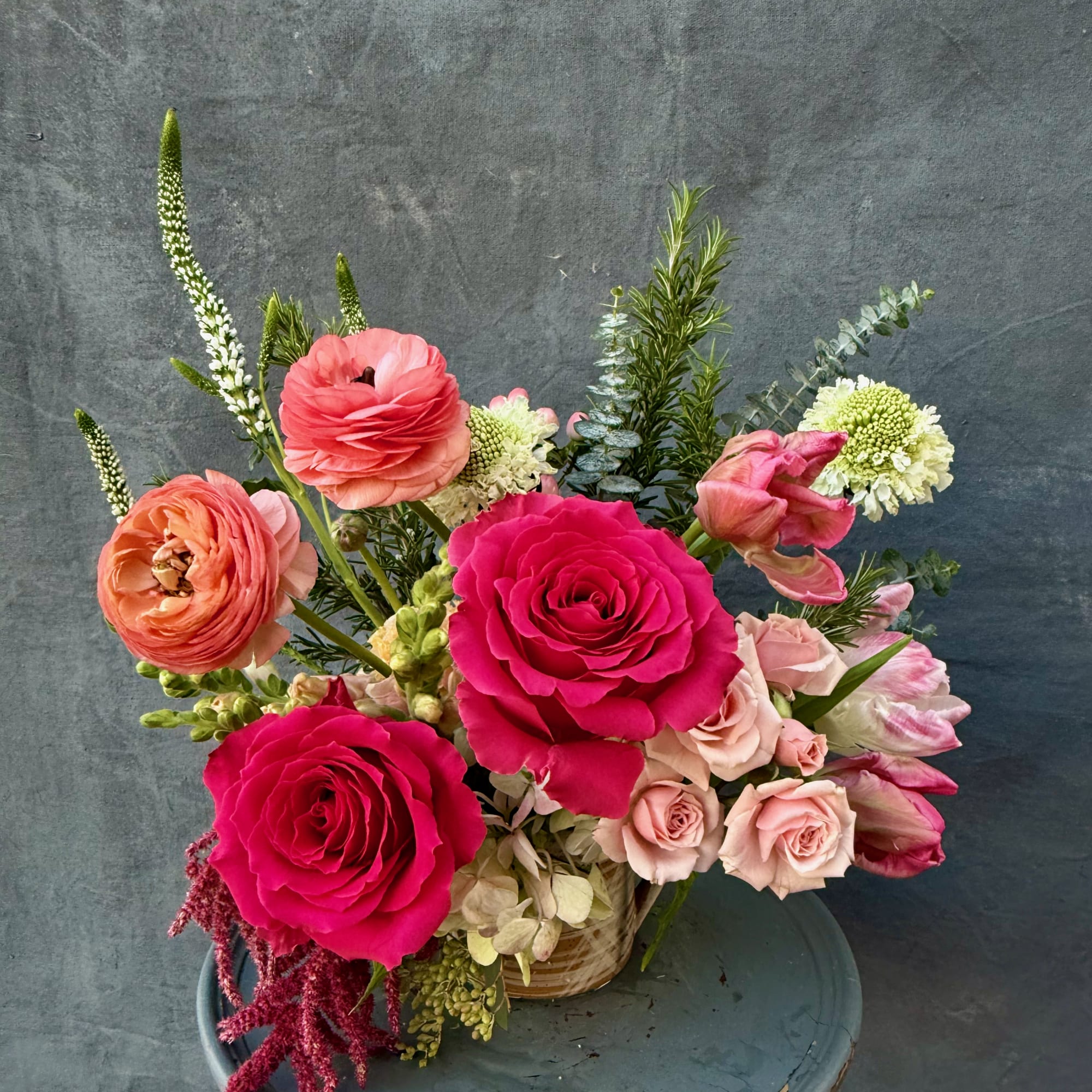 Pink and peach floral arrangement in a small basket vase