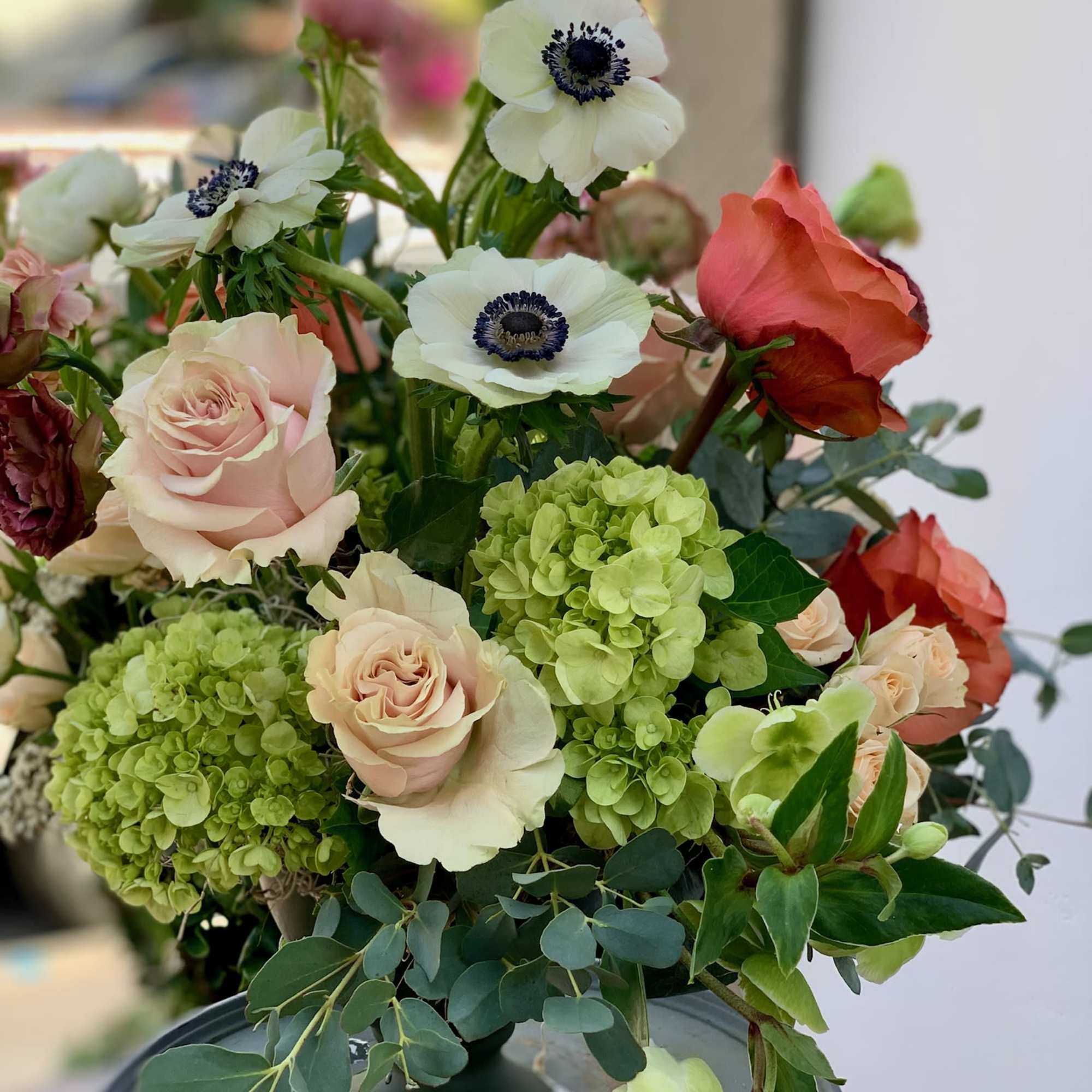 Mixed bouquet with pale roses, green hydrangeas, and white anemones in a vase