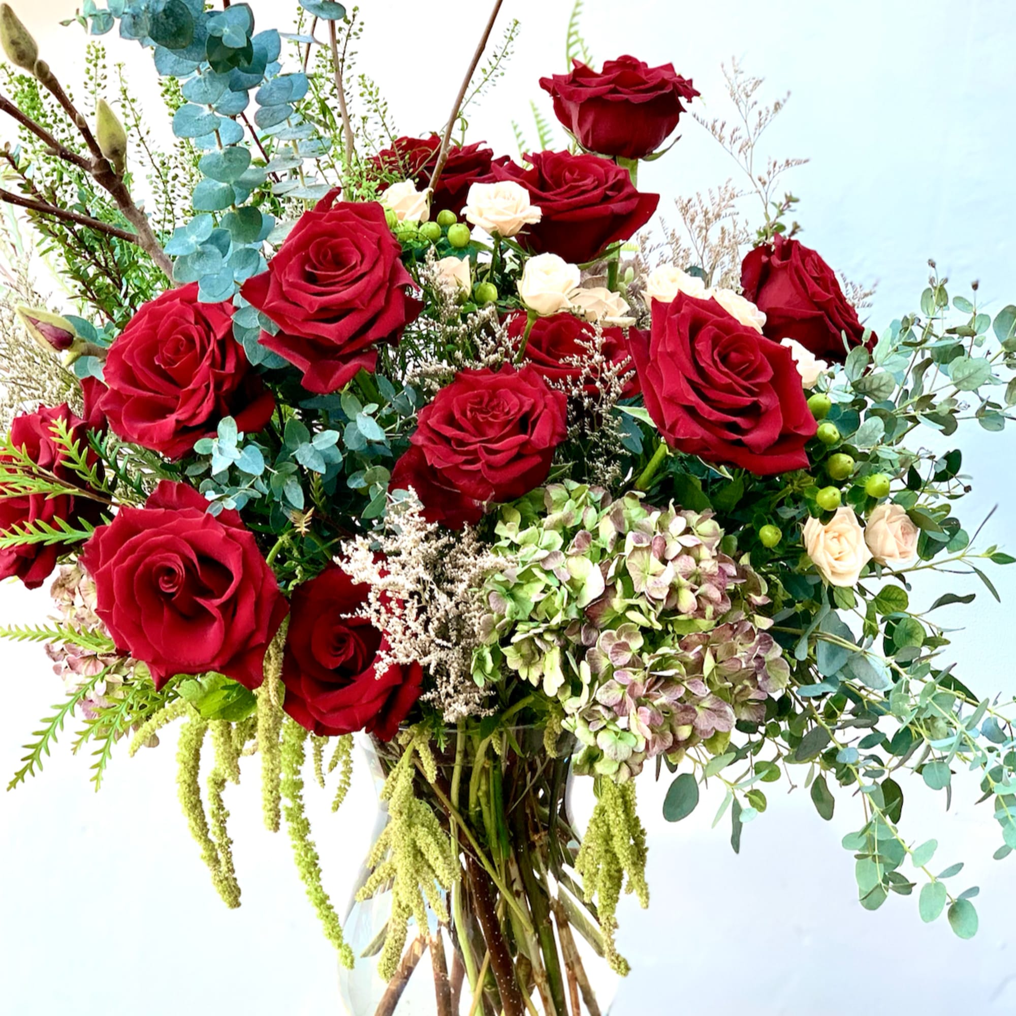 Bouquet of red roses with pale hydrangeas in a glass vase