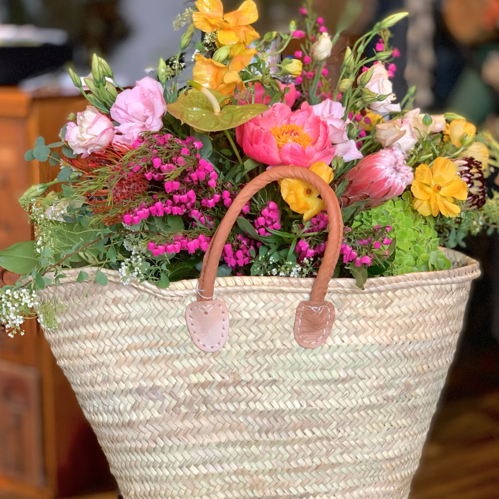 Mixed pink, yellow, and orange flowers in a woven basket