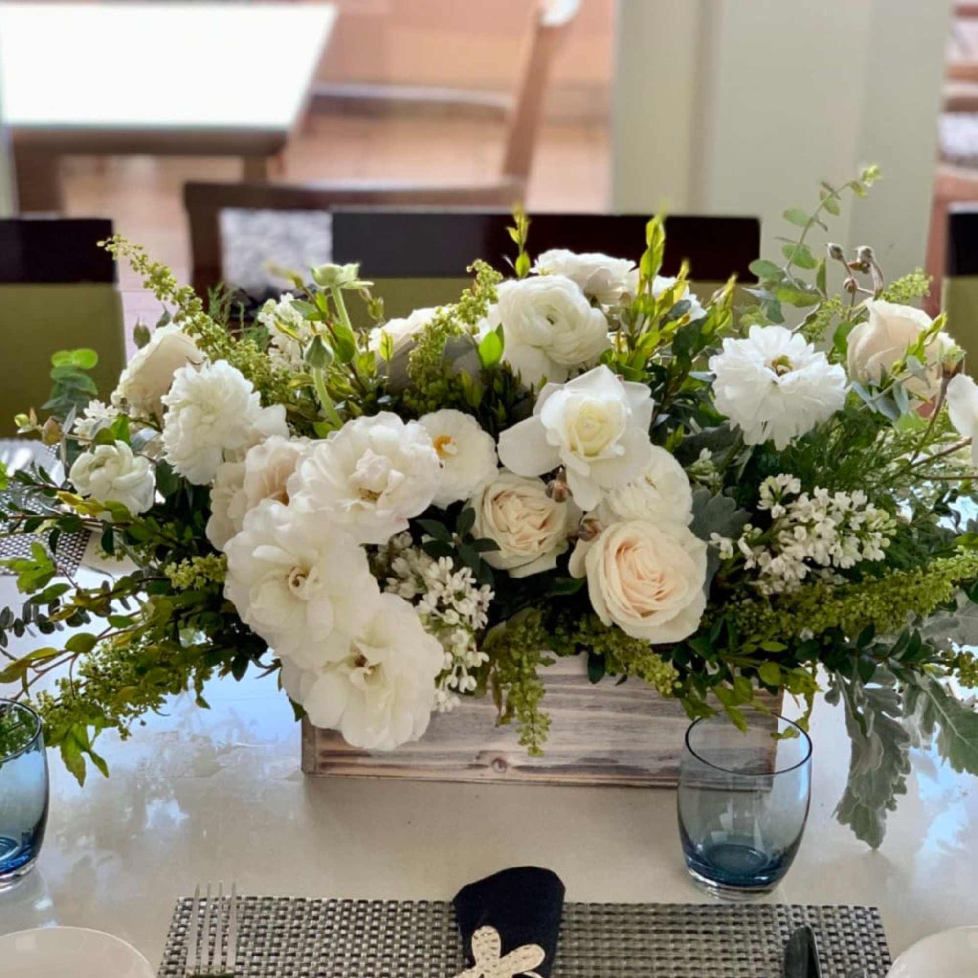 White floral centerpiece in a wooden box on a dining table
