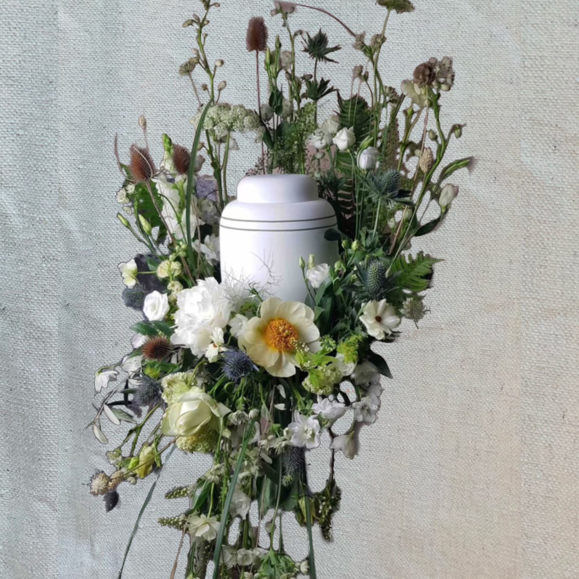White floral funeral urn arrangement with mixed blooms and tall stems