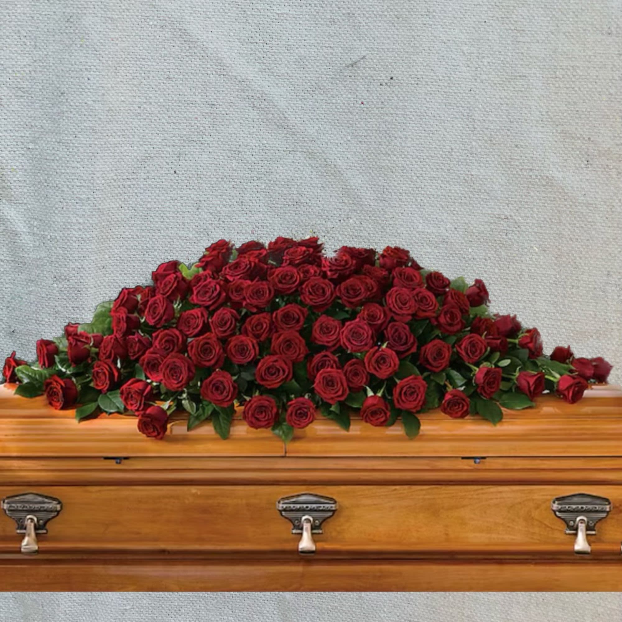 Red rose spray arranged on a wooden casket