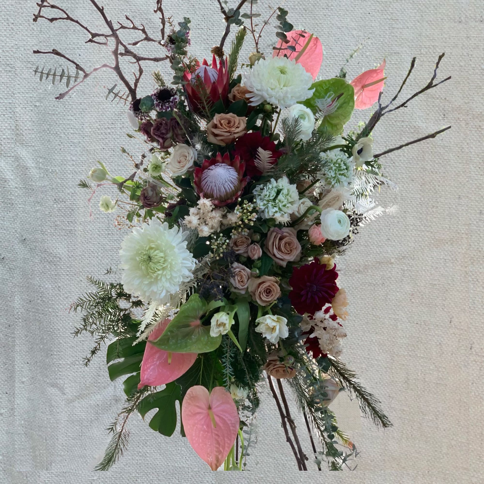 Tall mixed floral arrangement with pink anthuriums and white blooms