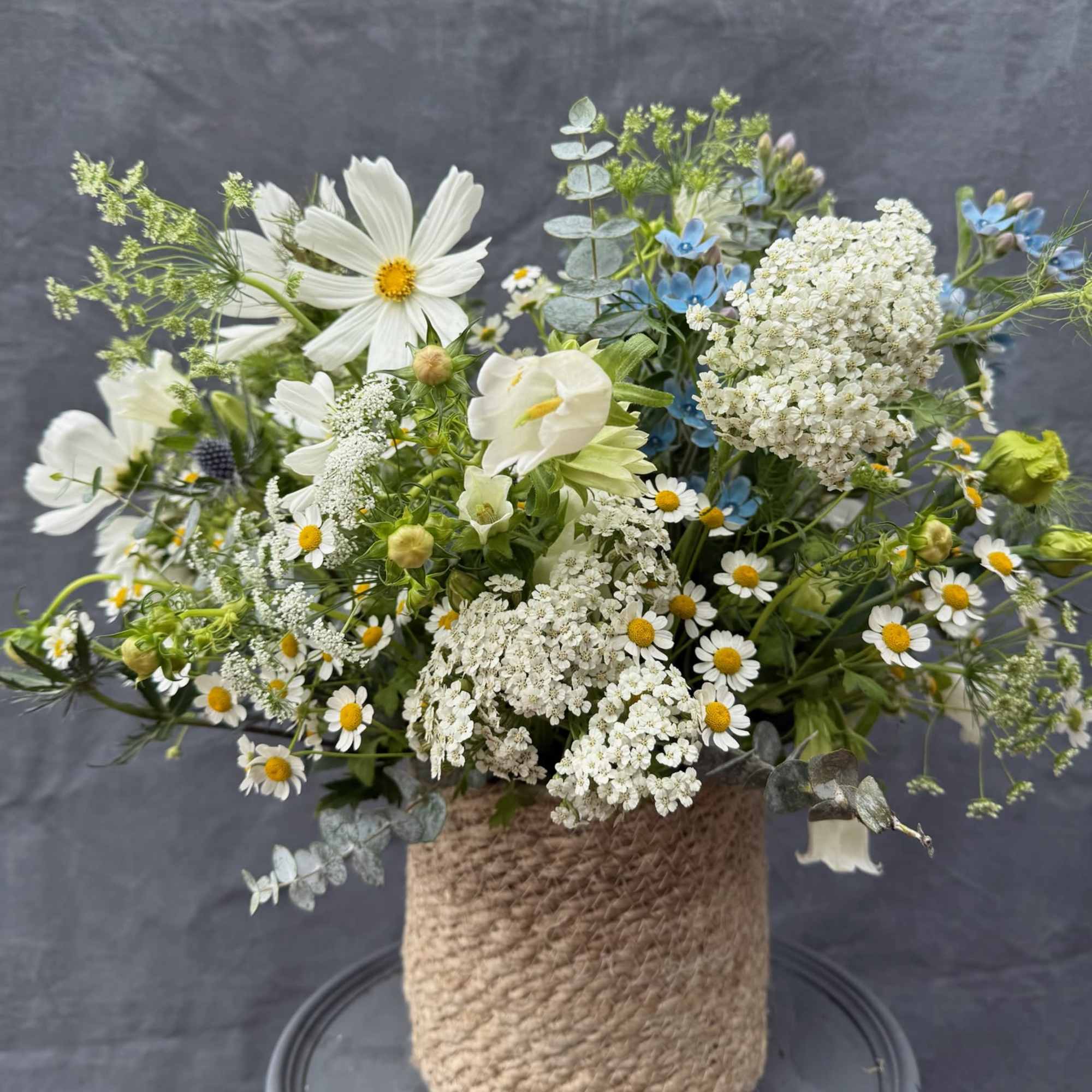Mixed white and blue flowers arranged in a rope-wrapped vase