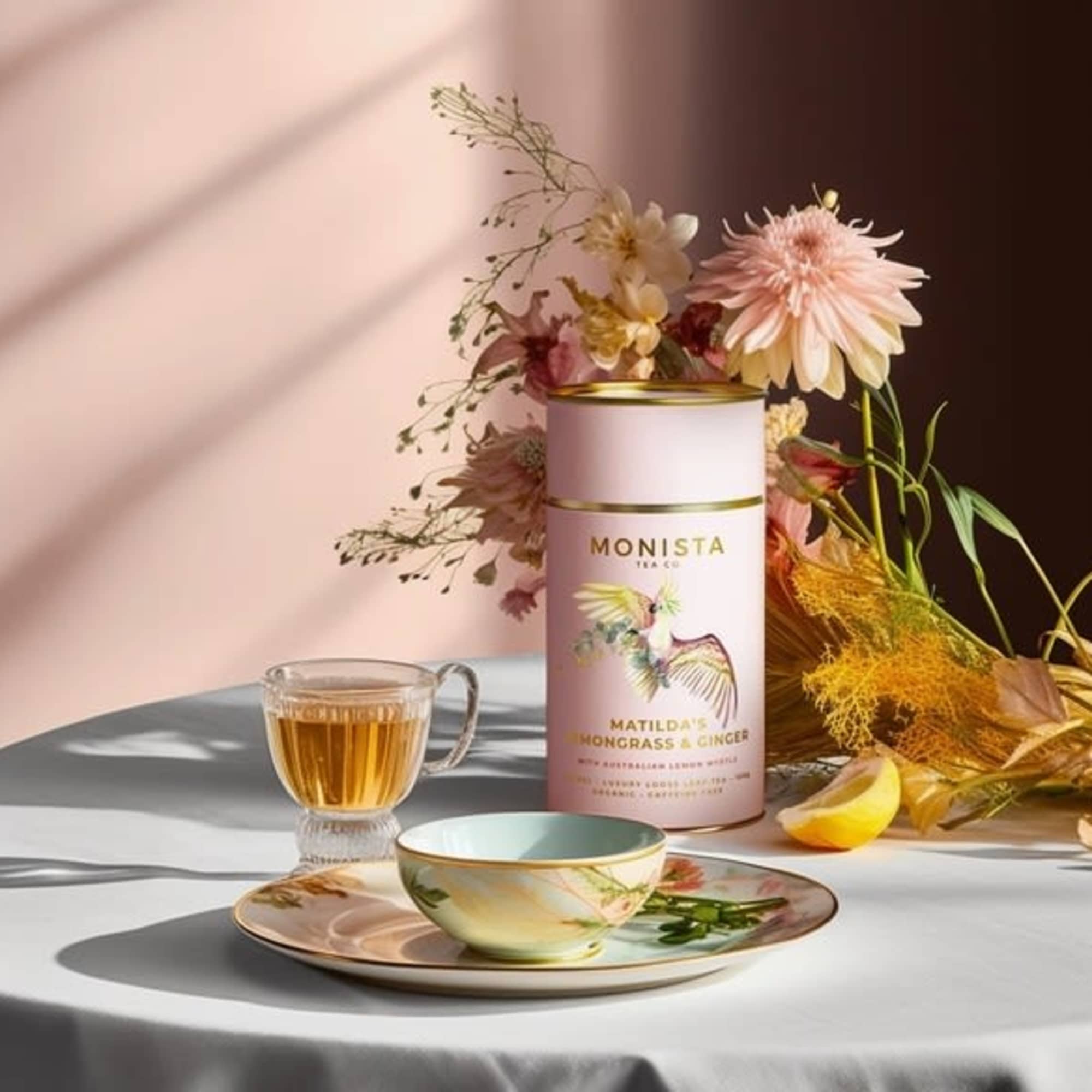 Tea tin with a small floral arrangement and a cup on a saucer