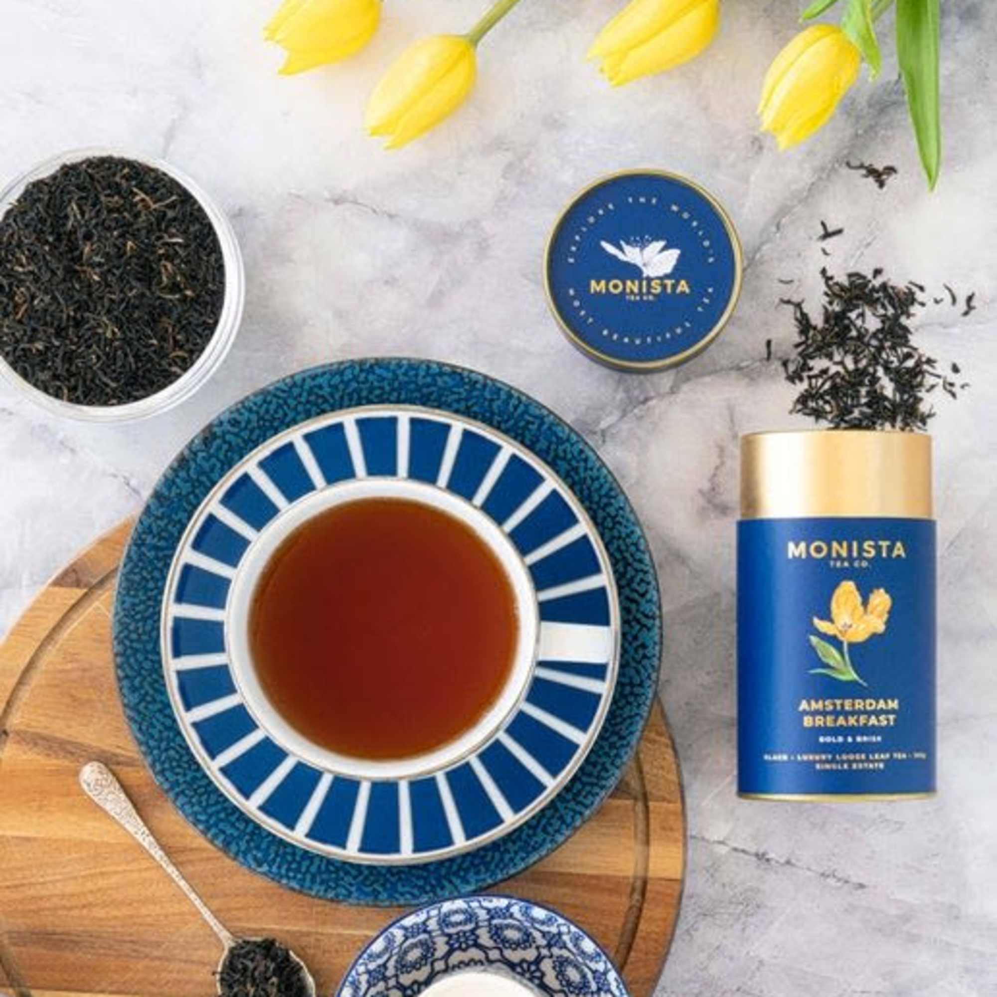 Tea set with loose tea, a cup, and yellow tulips