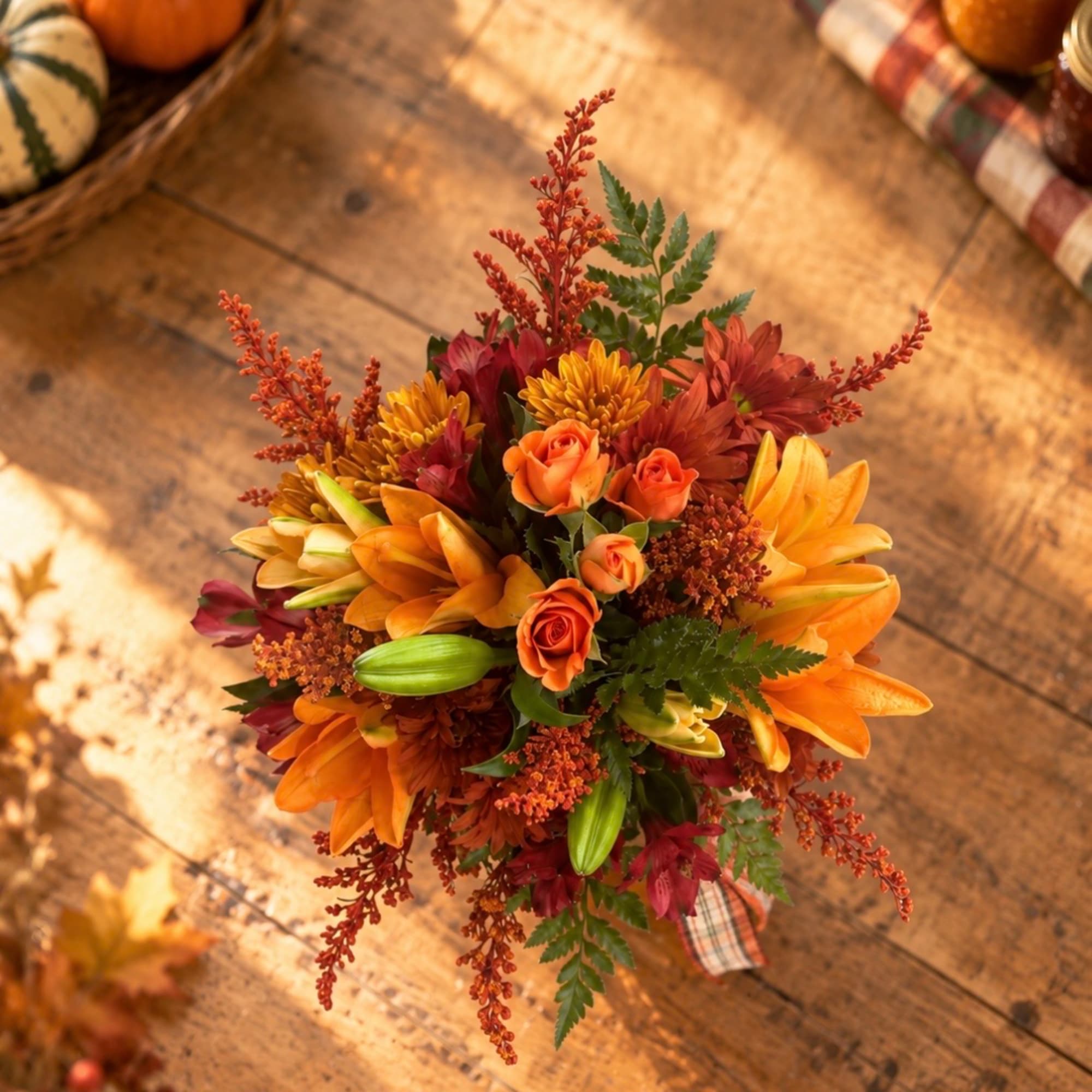 Autumn bouquet with orange lilies and small roses on a wooden table