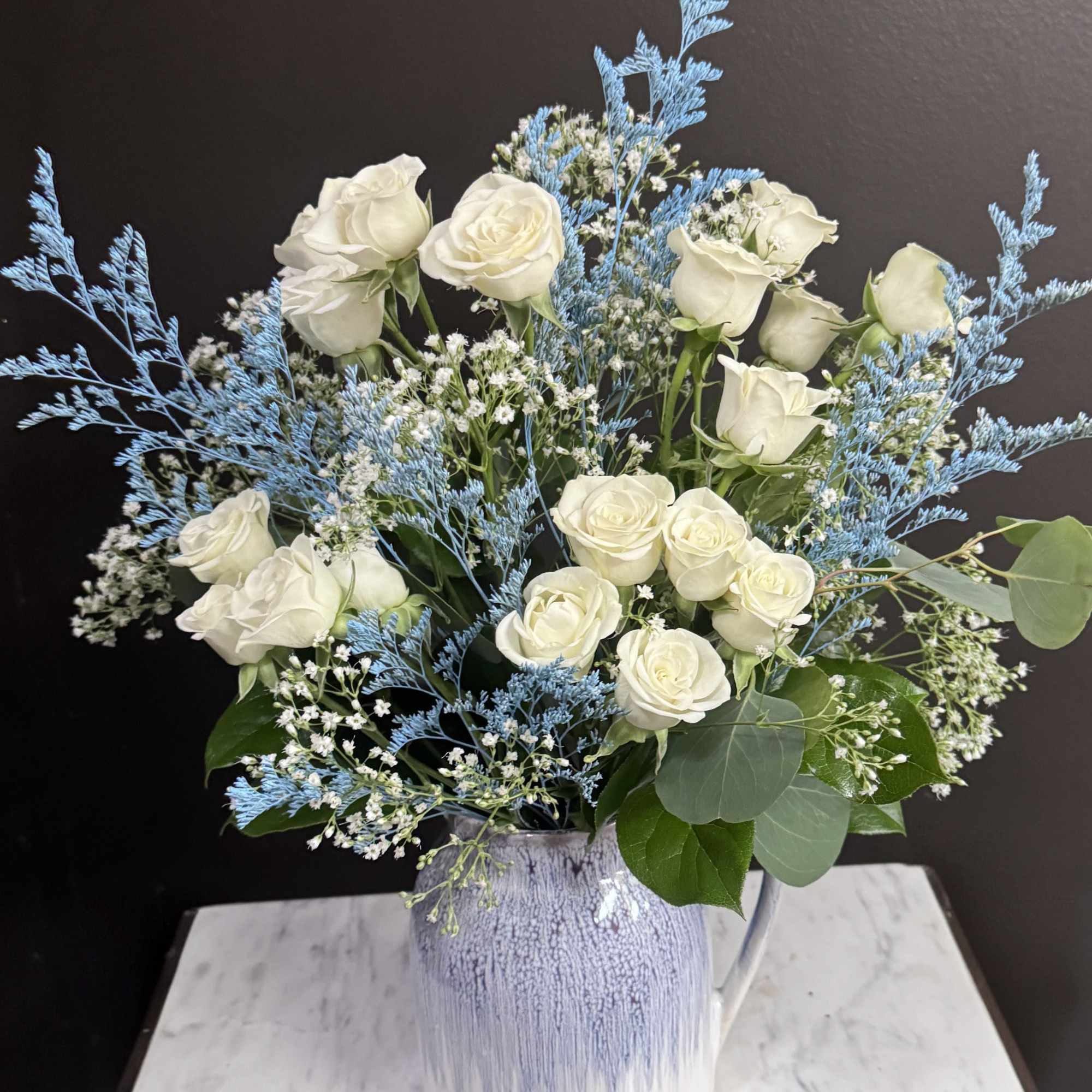 White roses in a blue-and-white ceramic vase with airy blue filler