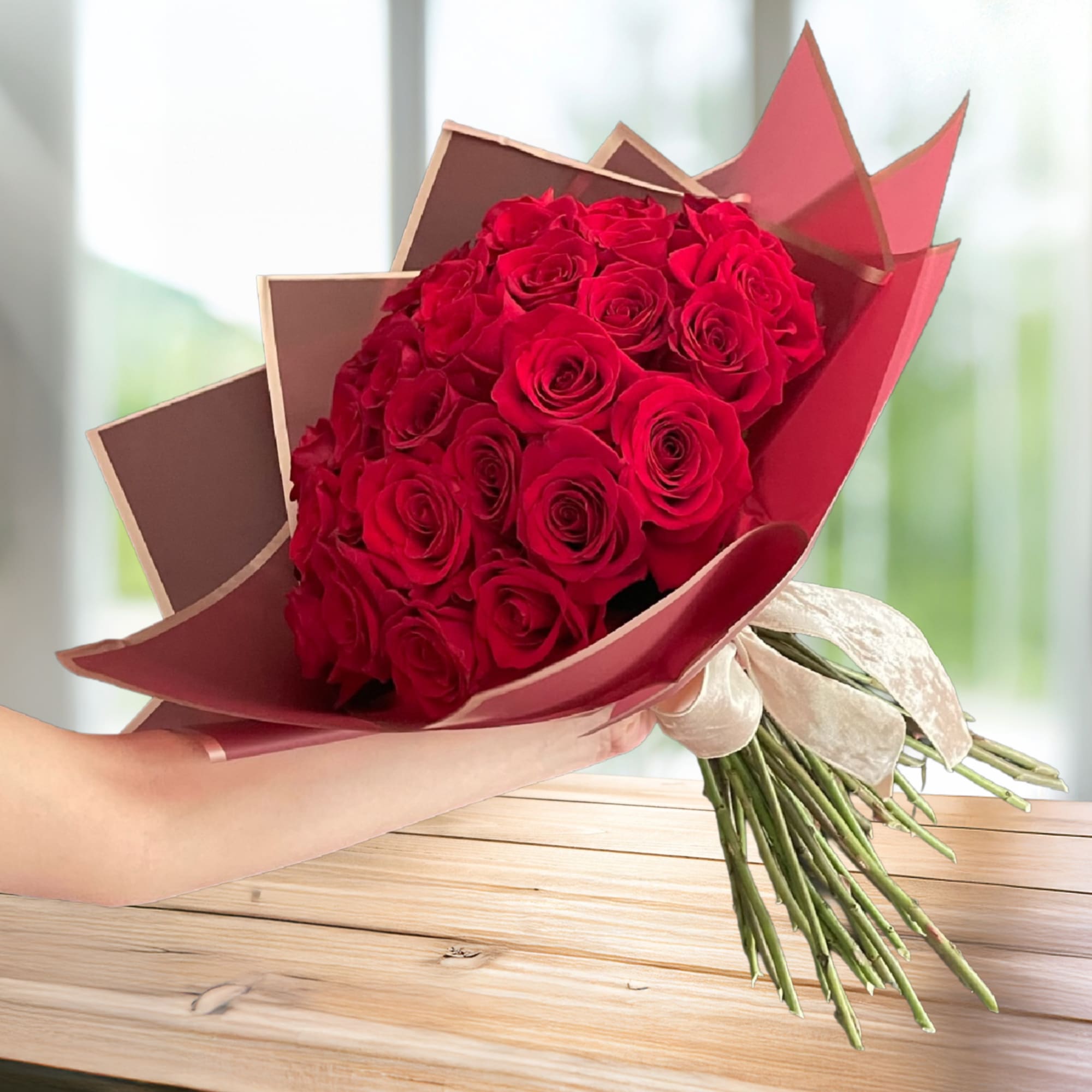 Bouquet of red roses wrapped in burgundy paper with a cream ribbon