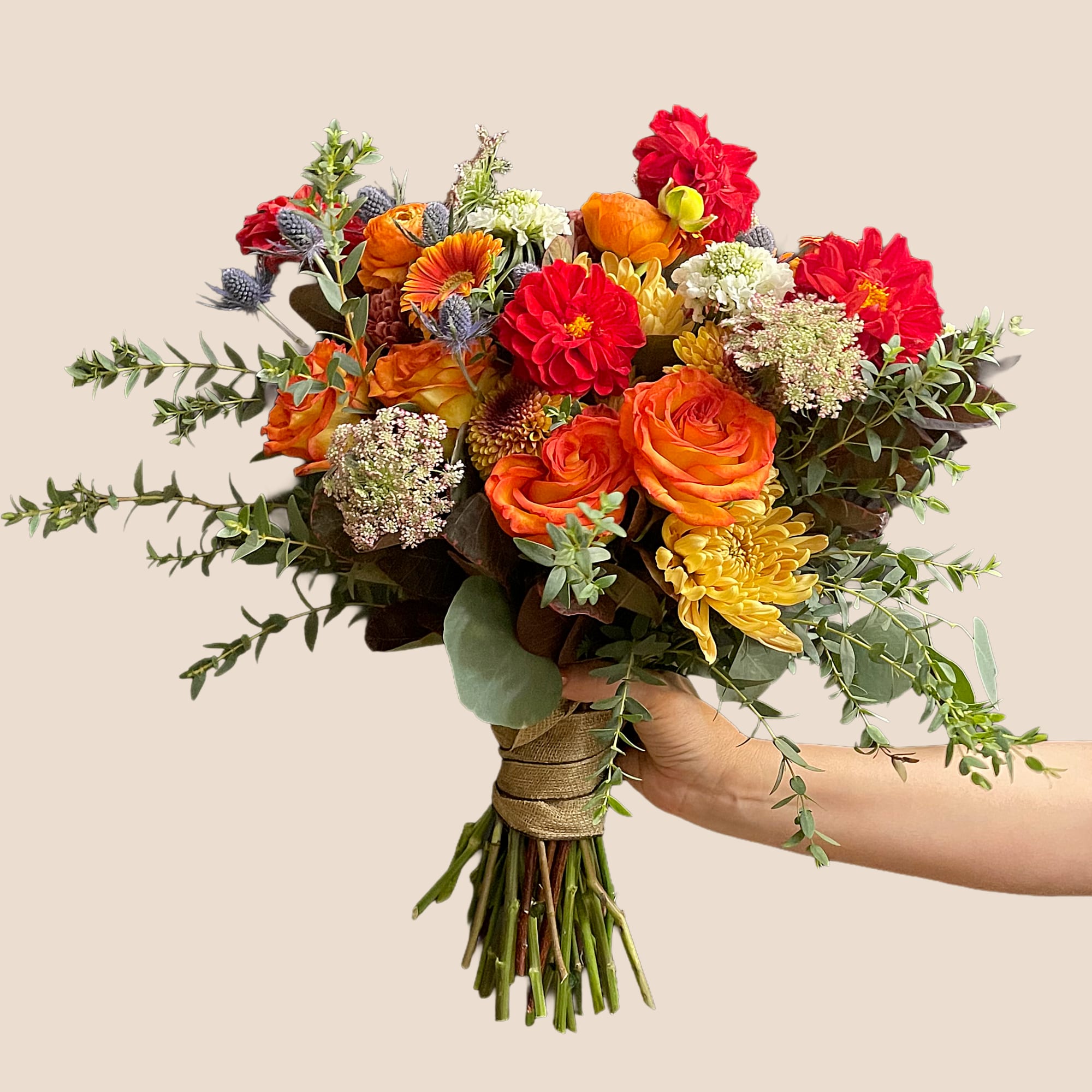 Handheld bouquet of orange, red, and yellow flowers