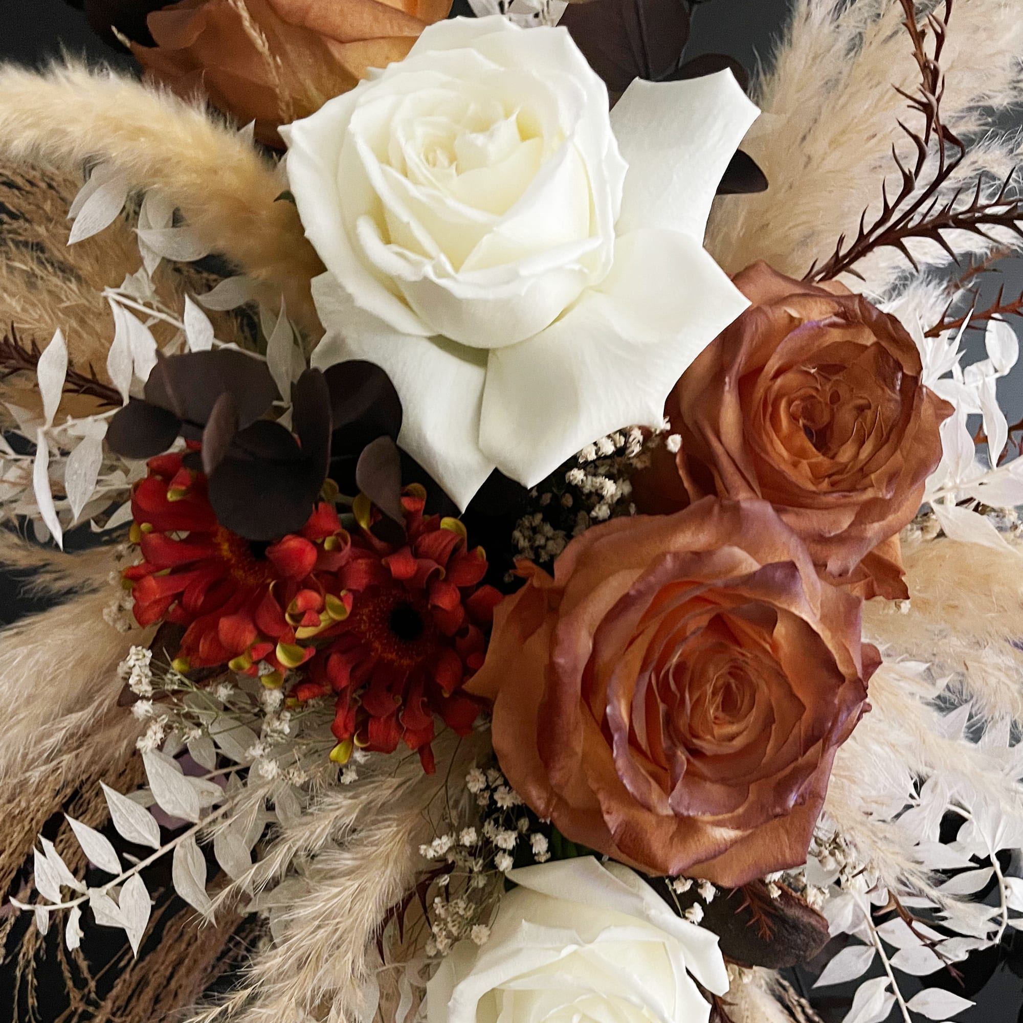 Bouquet of white and copper roses with red flowers and dried pampas accents