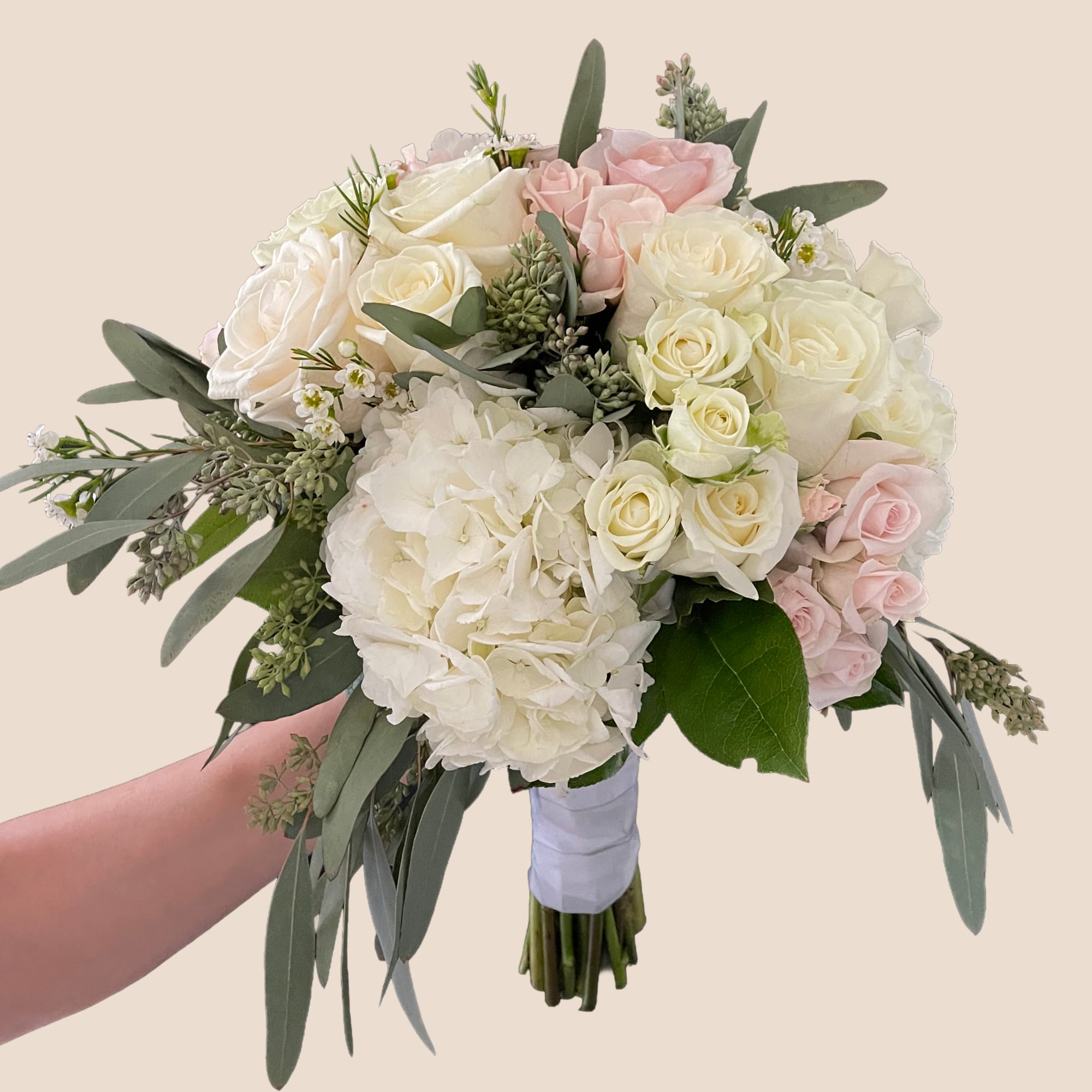 Handheld bouquet of white and blush roses with hydrangeas and eucalyptus