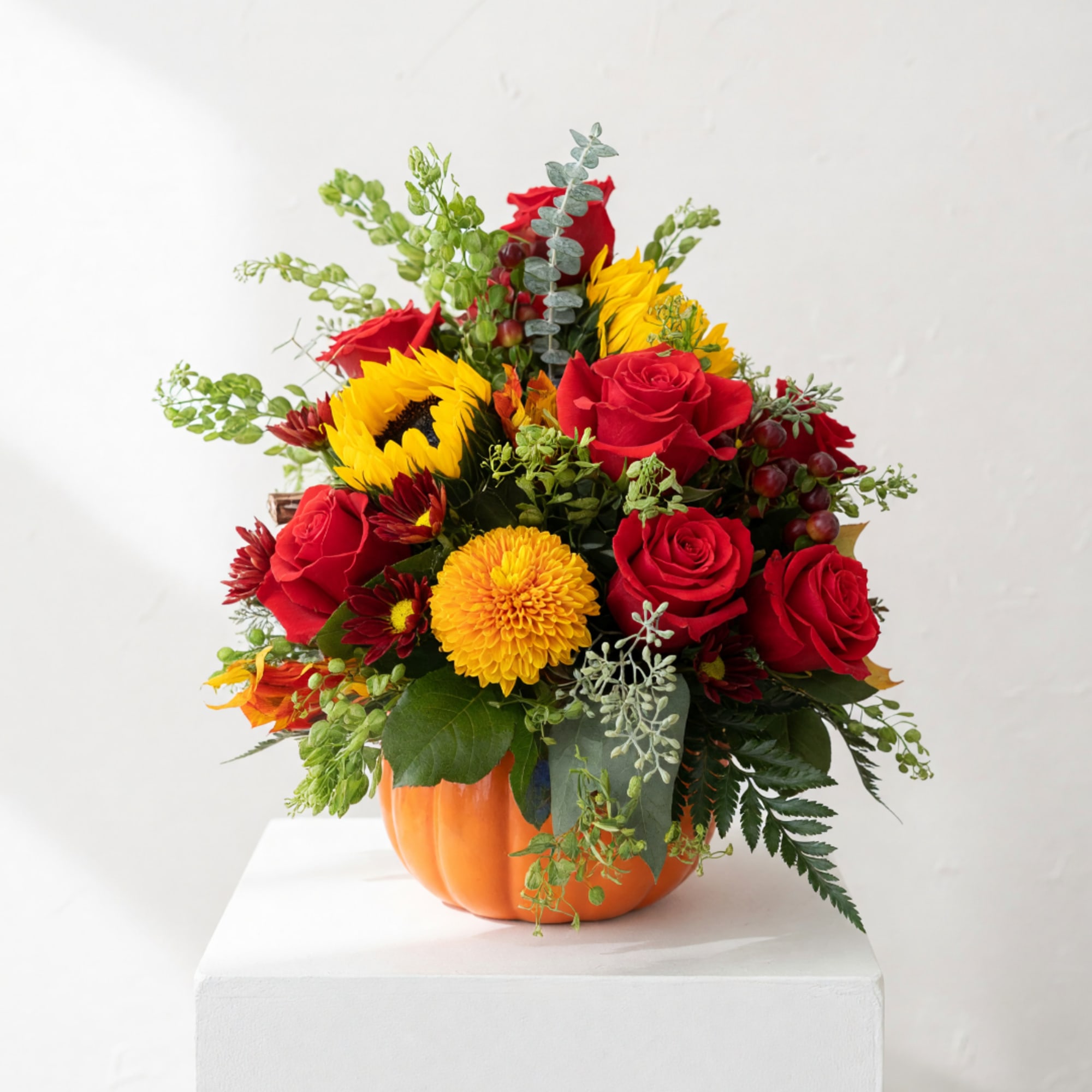 Bouquet of red roses and yellow sunflowers in an orange pumpkin container