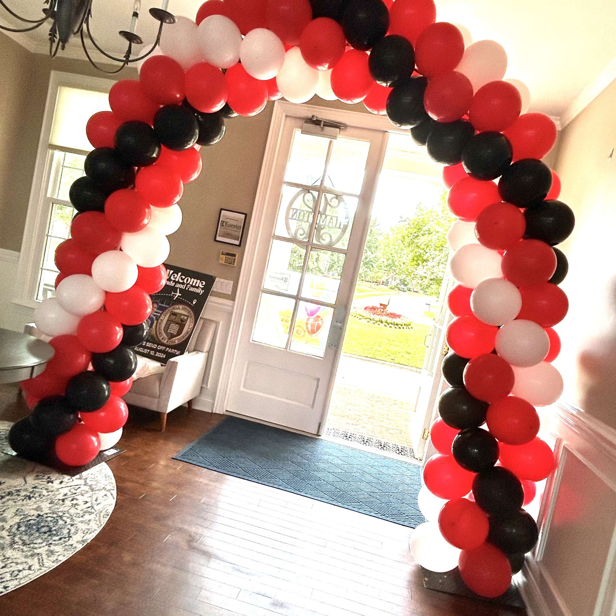 Red, black, and white balloon arch in a doorway
