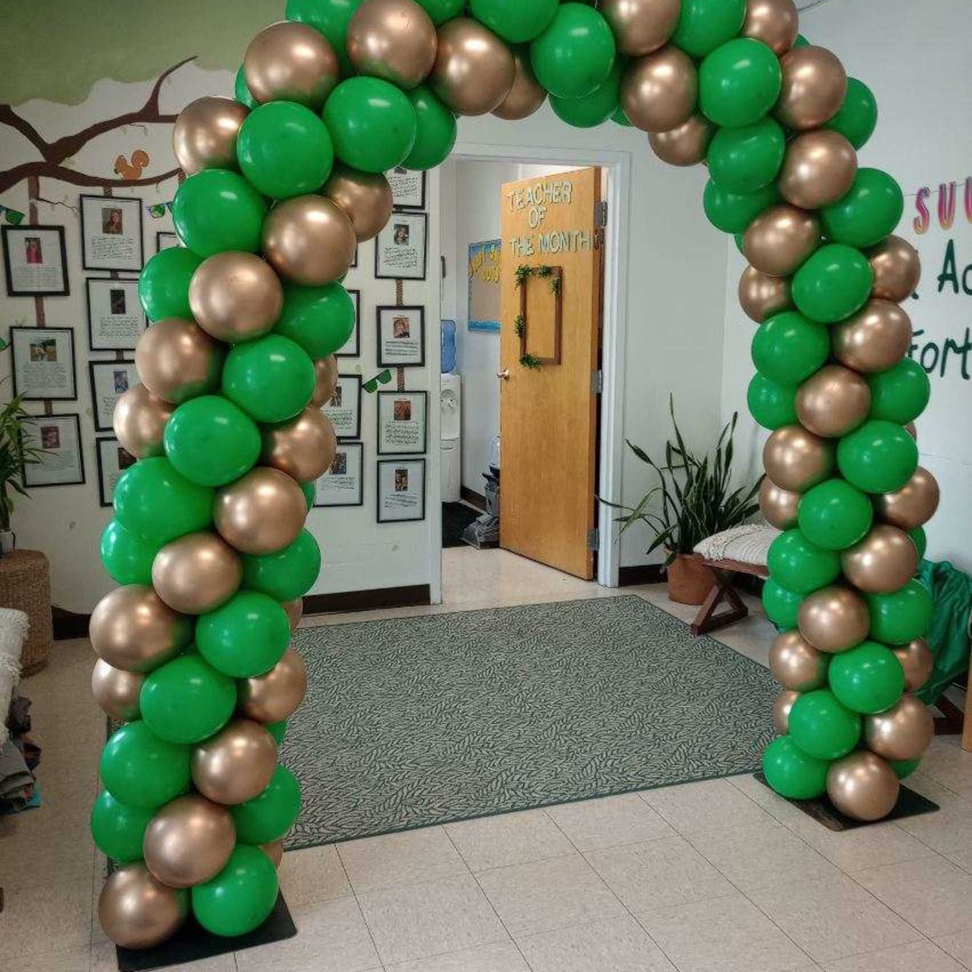Green and gold balloon arch in a room