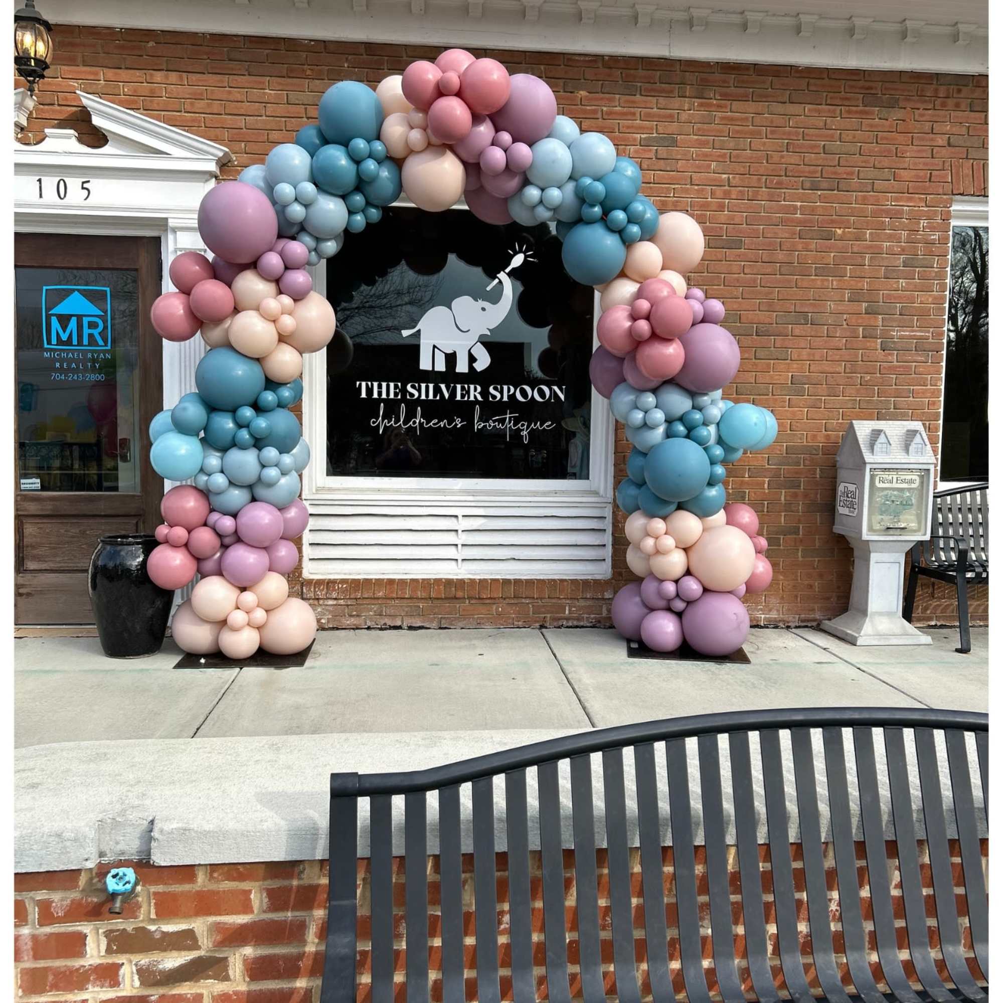 Pastel balloon arch framing a storefront window and door