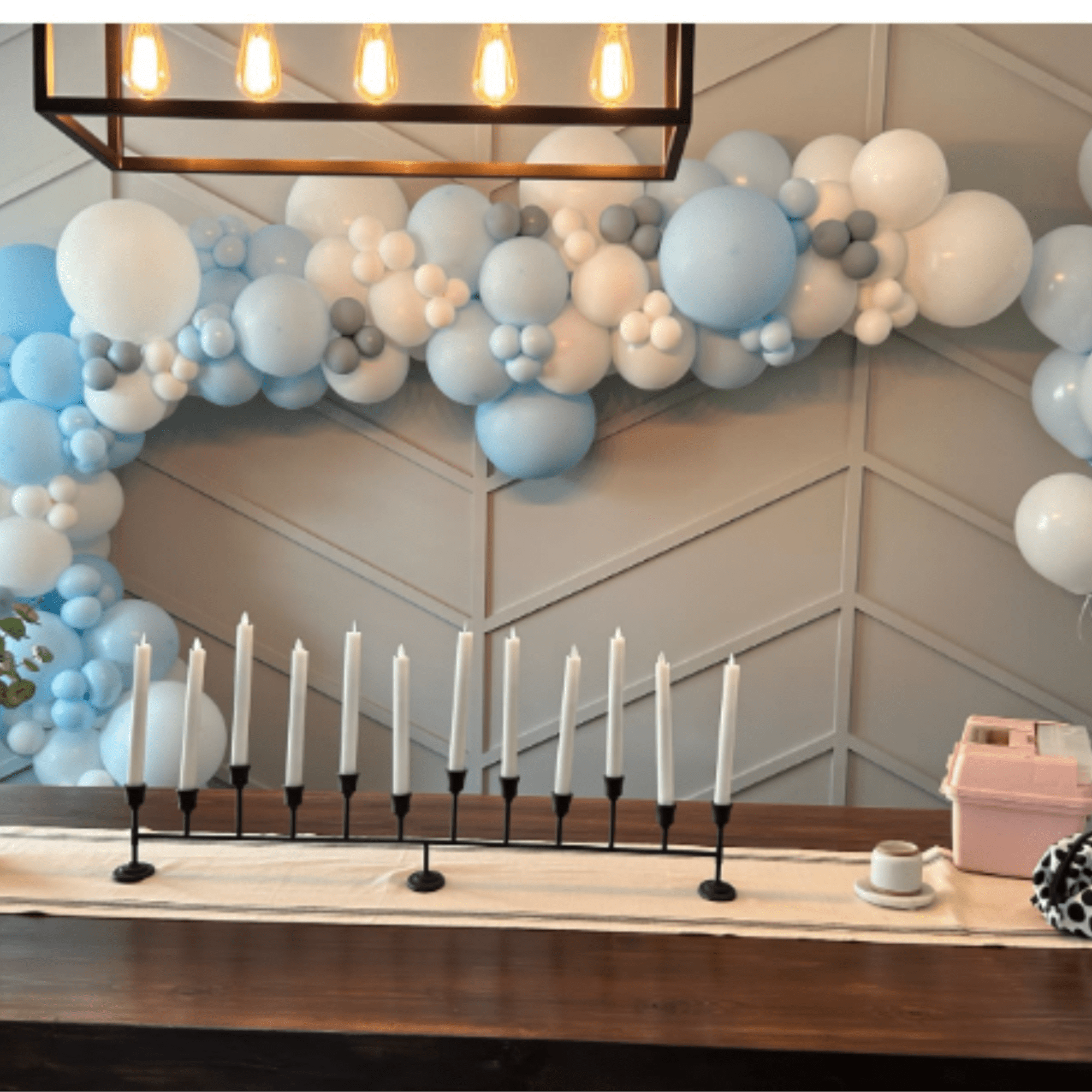 Blue and white balloon garland above a table with candles